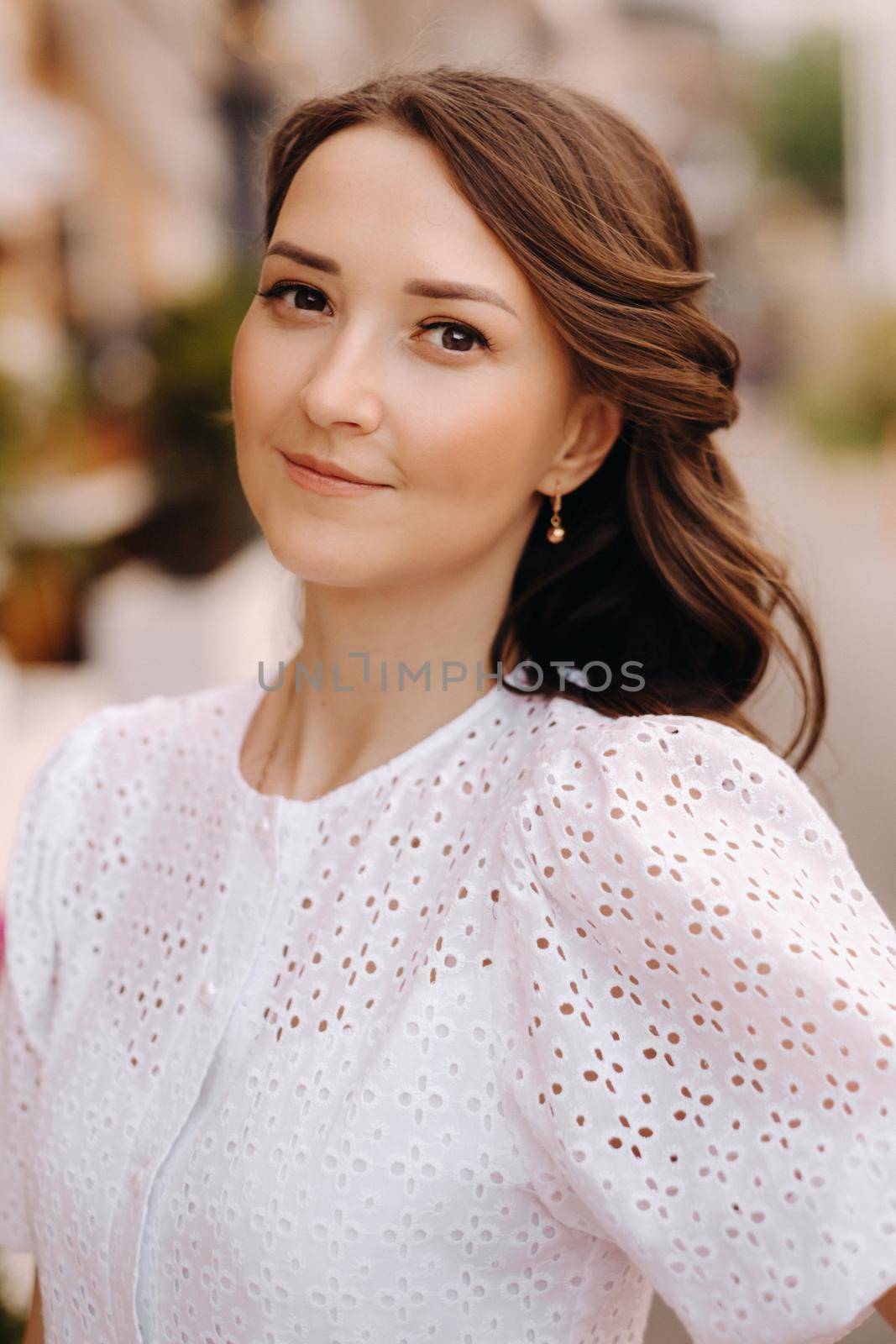 A beautiful woman in a white dress at sunset in the city. Evening street photography.