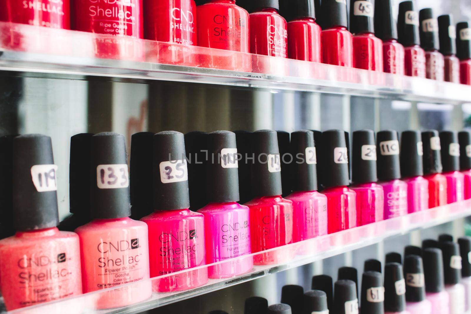 Rabat / Malta - December 8 2019: Rows of bottles of pink and red nail polish on shelves in a beauty spa by tennesseewitney