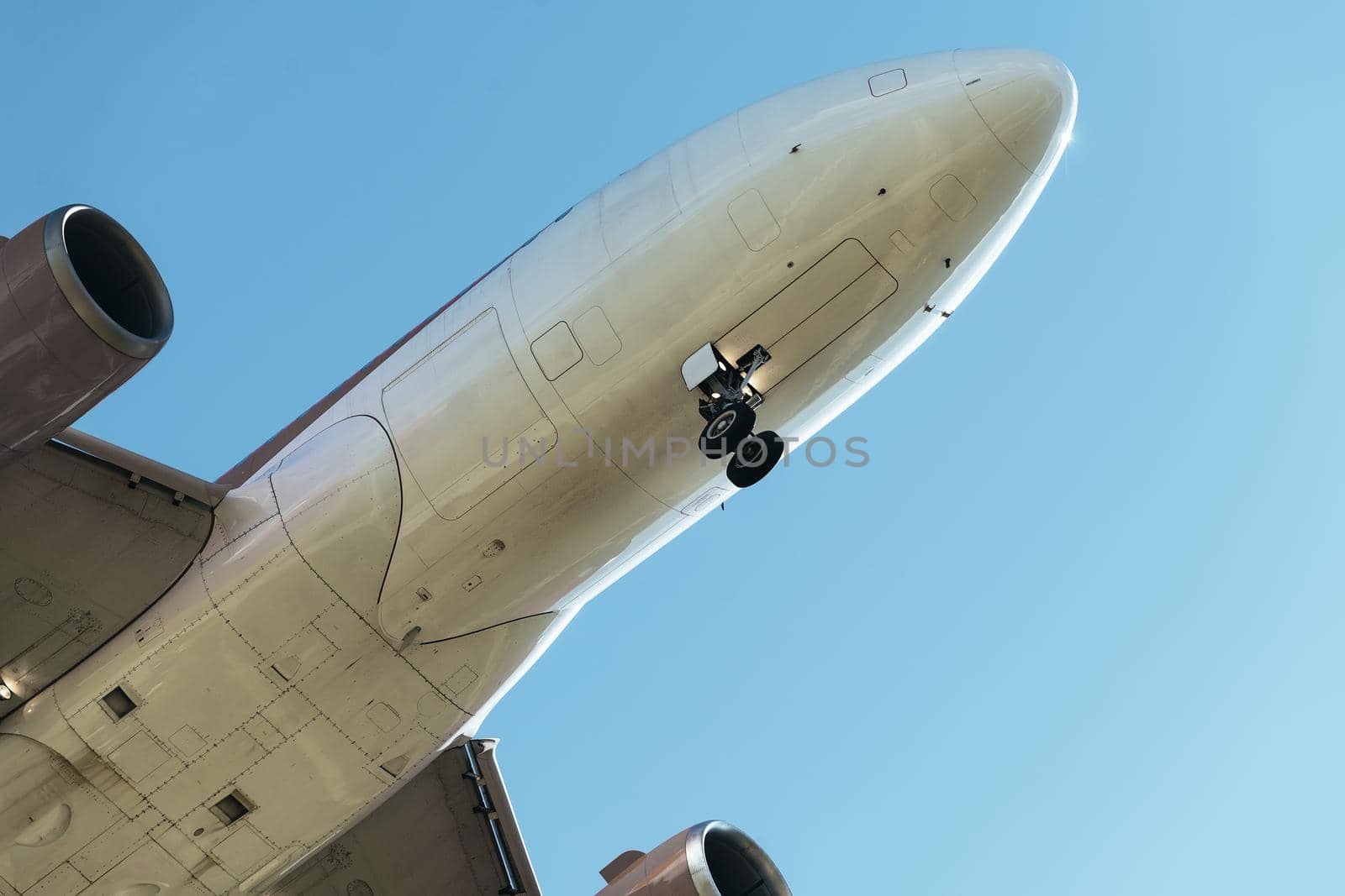 detail of the nose of a plane flying seen from below with the landing gear deployed, travel concept, copy space for text