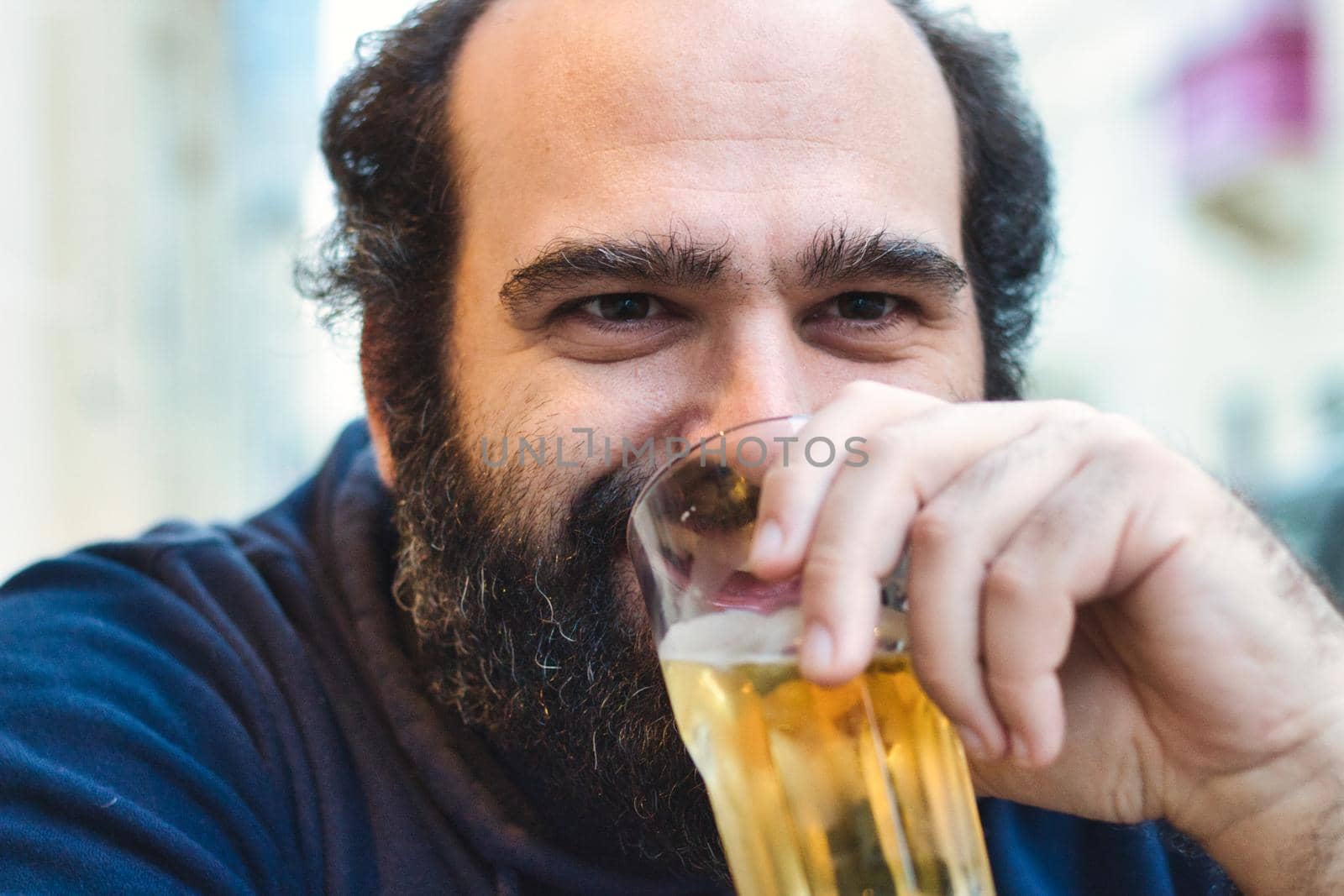 Bearded man drinking lager beer from a glass