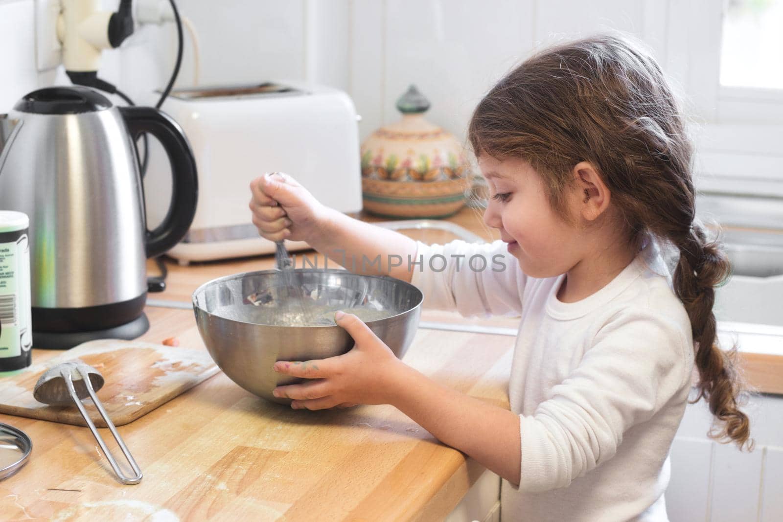 Cute little girl stirring with a whisk and mixing bowl in the kitchen by tennesseewitney