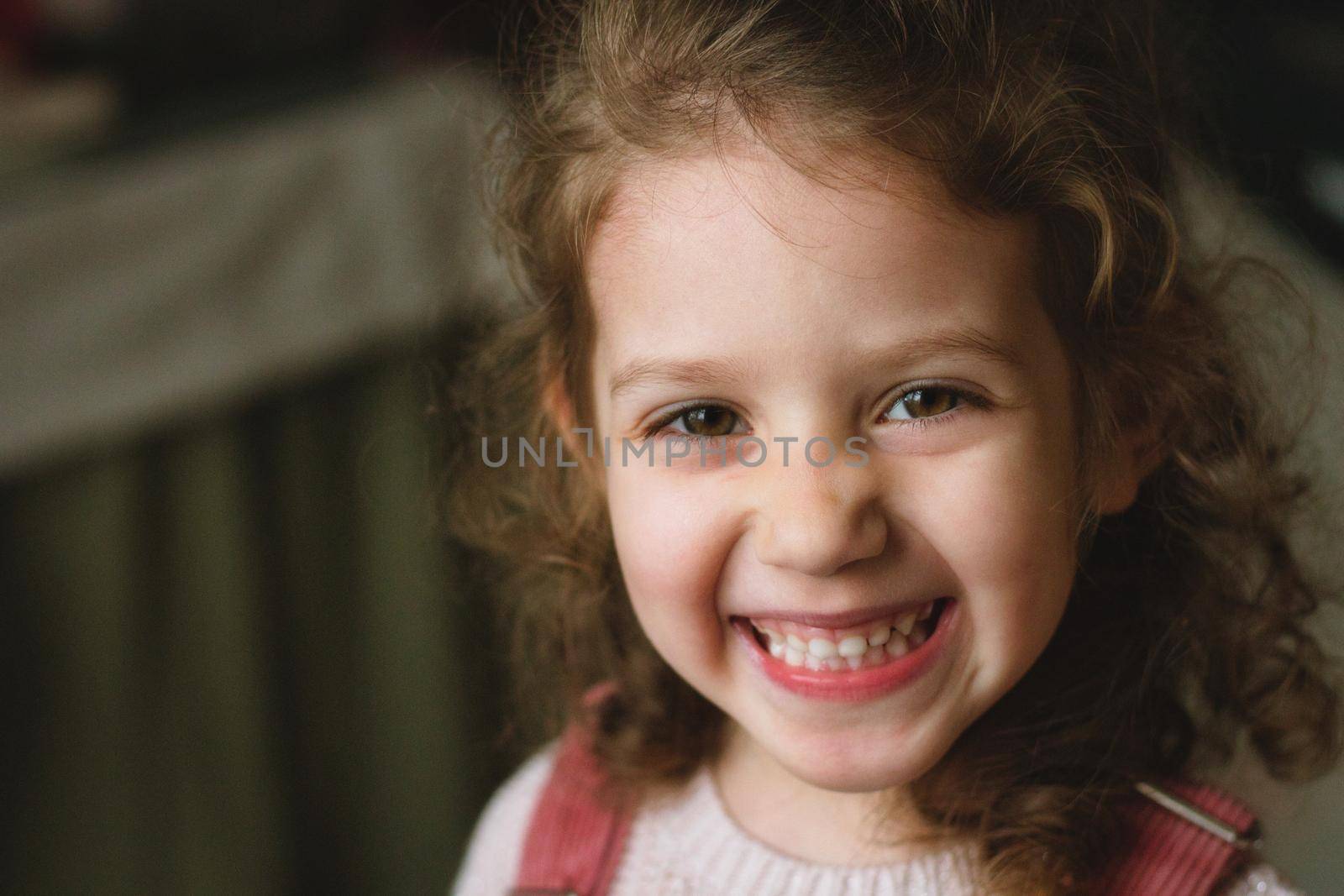 Close-up portrait of a cute little white caucasian girl with a cheeky smile and expression on her face looking directly at the camera