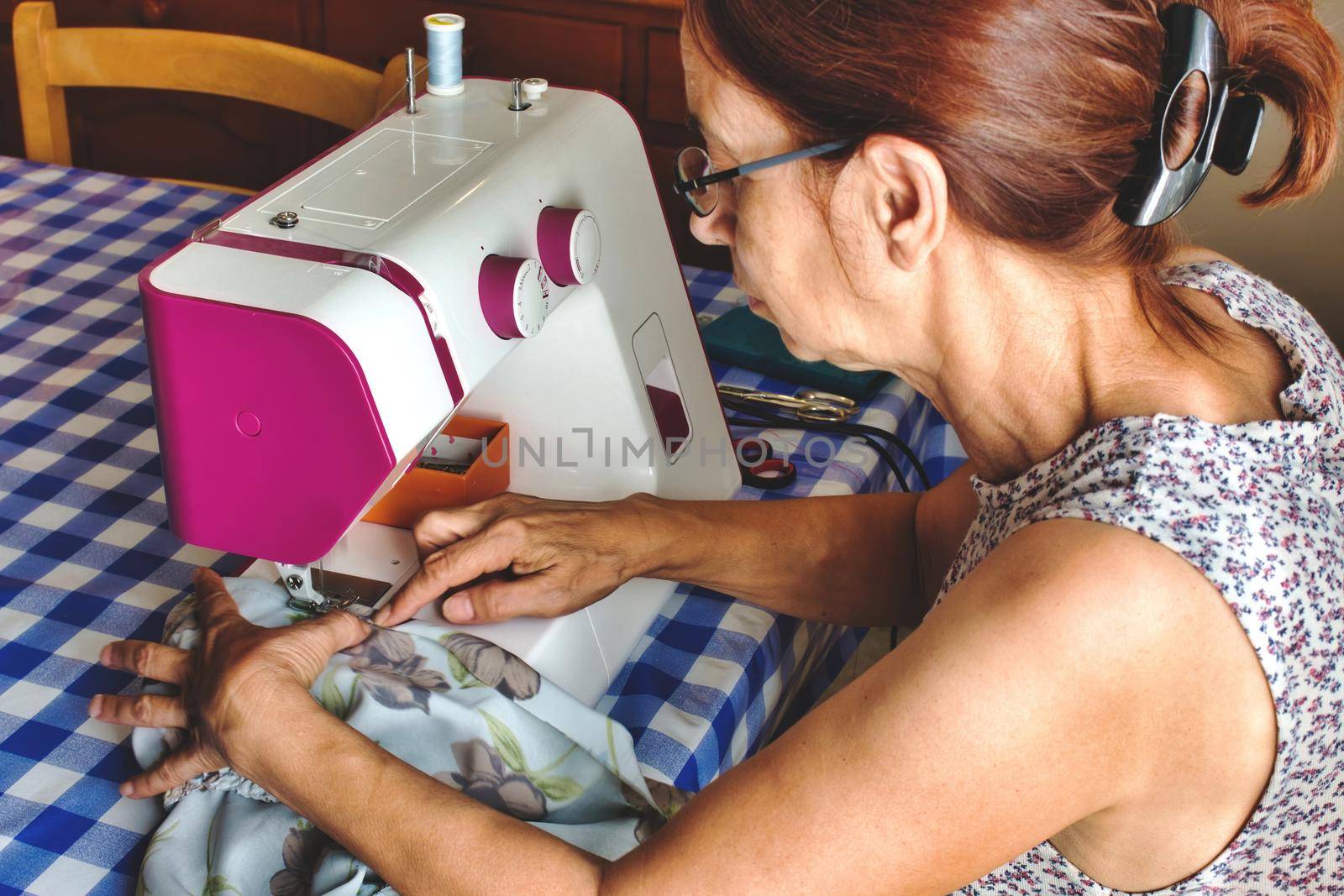 Middle-aged woman using a sewing machine to make a dress by tennesseewitney