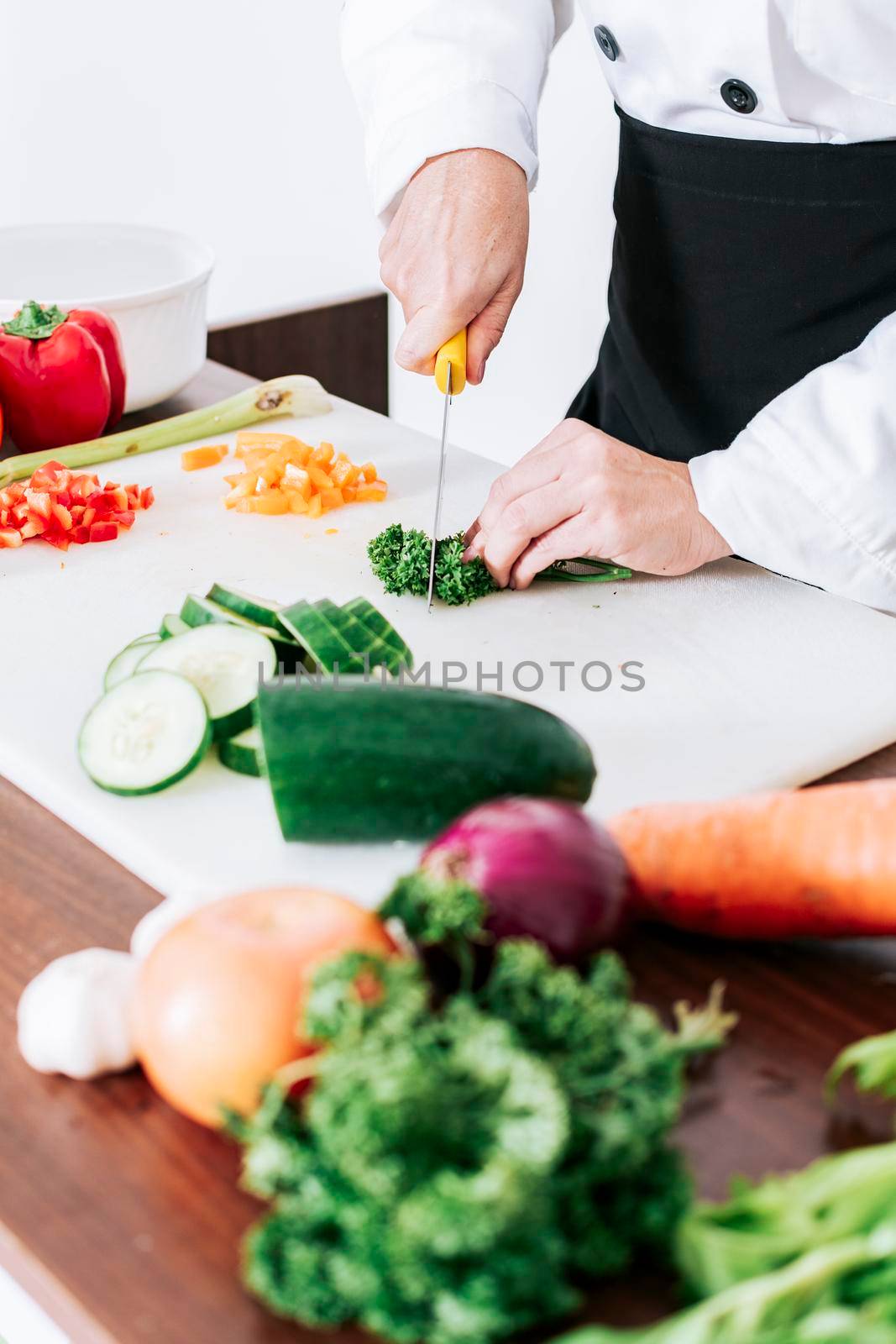 Hands of female chef cutting vegetables, chef hands preparing and cutting vegetables, Close up of a female chef cutting vegetables by isaiphoto