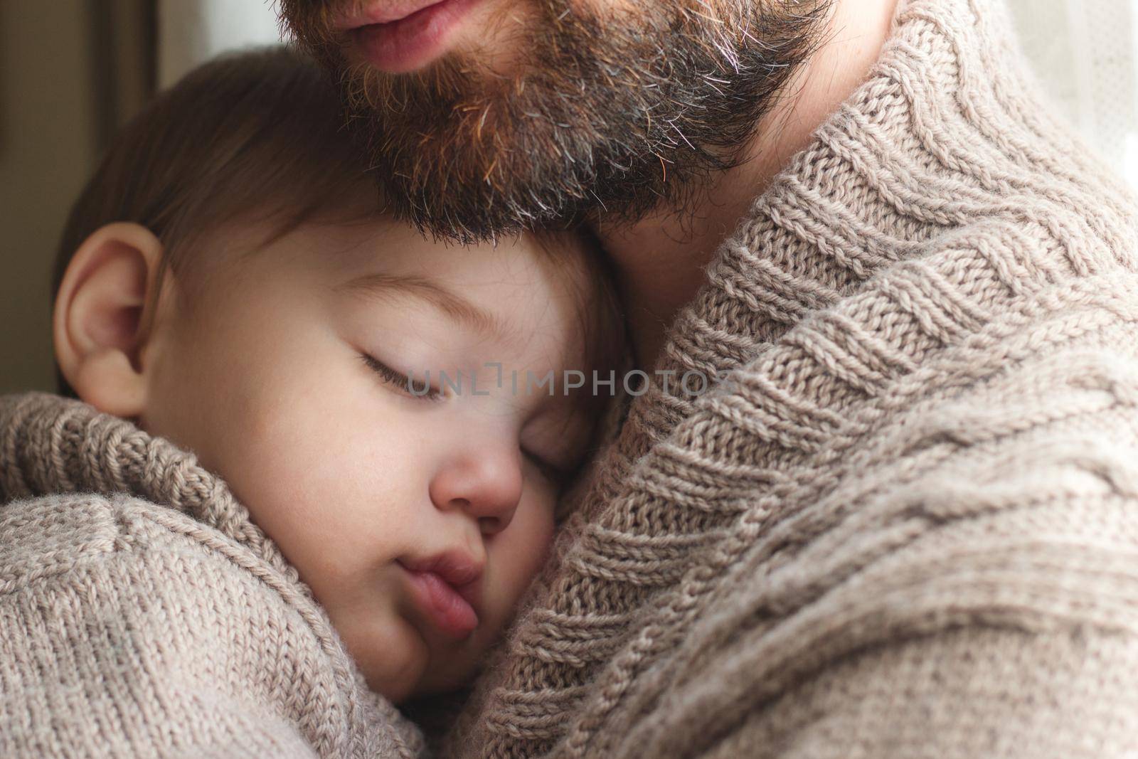 Father holding a small infant child sleeping in his arms