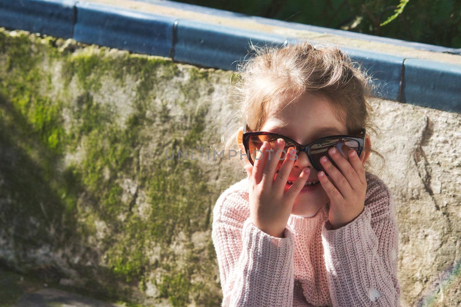 Cute little girl playfully wearing big sunglasses and having fun by tennesseewitney