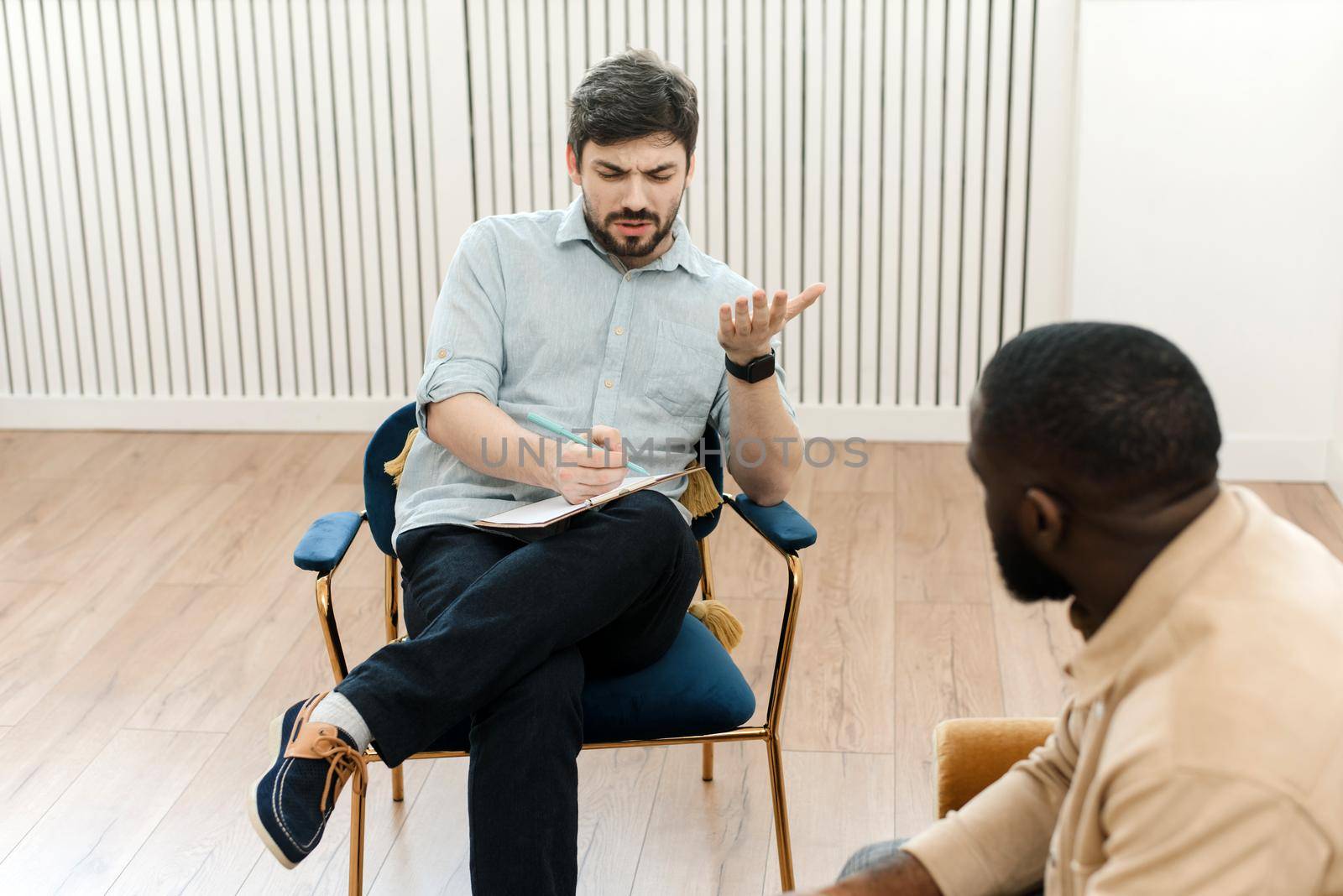 A black male patient undergoing a psychotherapy session with a counselor at a mental health clinic. Young man with emotional problems consults professional therapist.