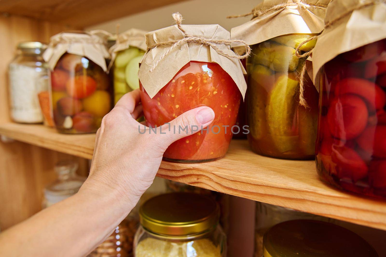 Storage of food in the kitchen in pantry. Pickled canned vegetables and fruits on the shelf, jar of tomatoes close-up. Cooking at home, homemade preservation, household