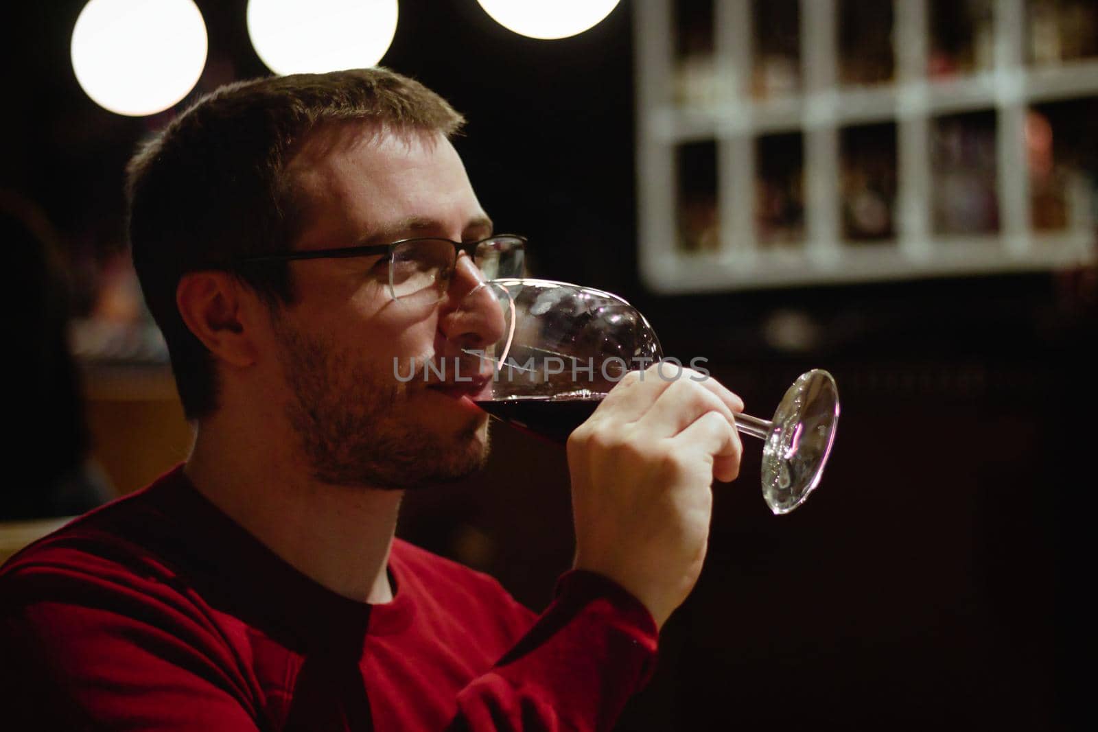 Young man in a restaurant drinking red wine from a glass by tennesseewitney
