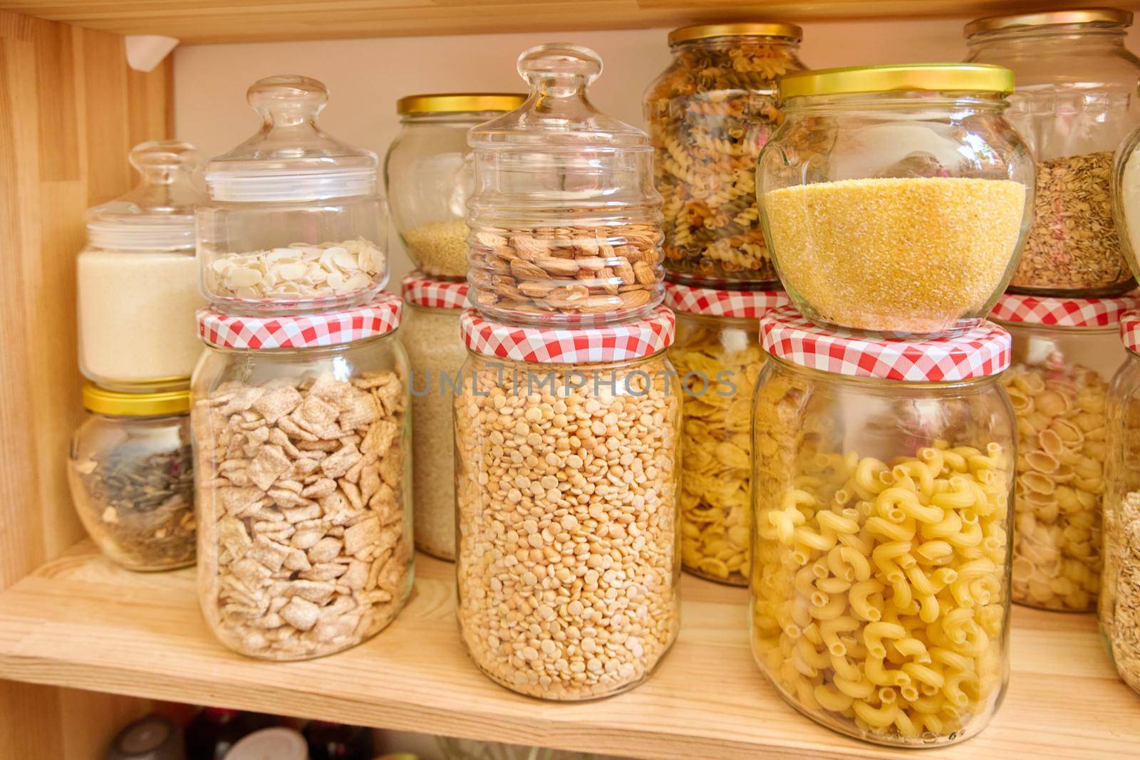 Storage of food in the kitchen in the pantry. Cereals, spices, pasta, nuts, flour in jars and containers, kitchen utensils. Cooking at home, stocking food, household