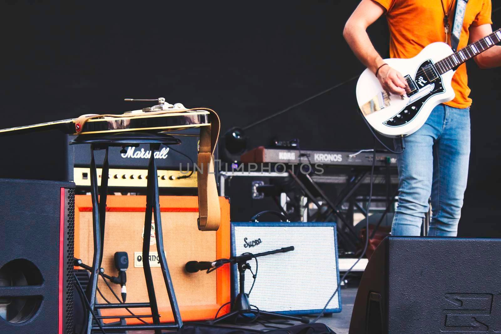 A guitarist on stage surrounded by musical equipment and electric guitar amplifiers by tennesseewitney