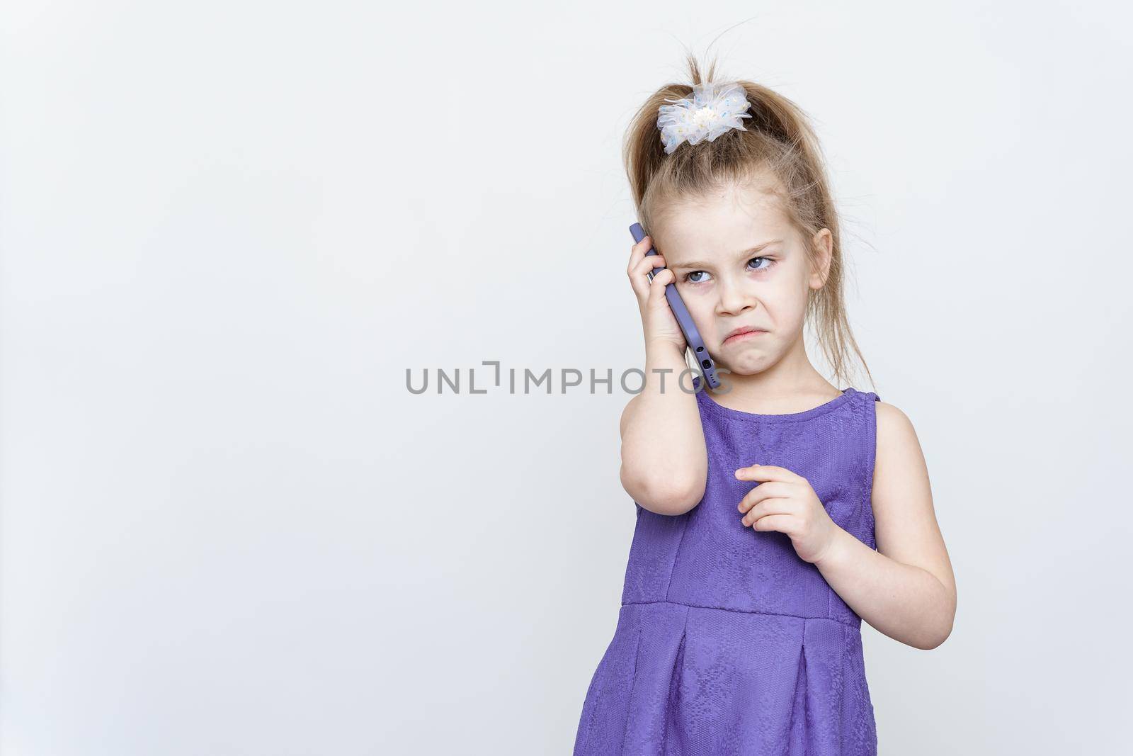 angry little girl in blue dress talking on the phone