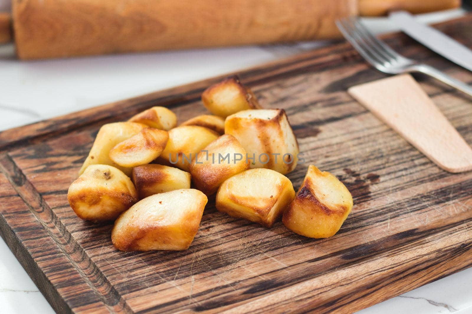 Roasted potatoes on a wooden chopping board on a kitchen worktop