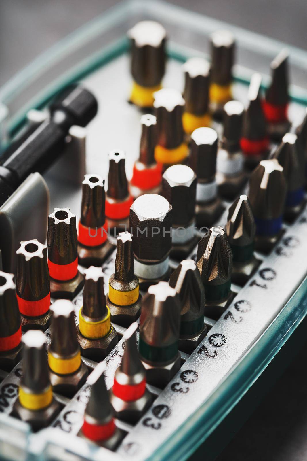 A set of metal power bits in a box on a gray background, for repair and maintenance