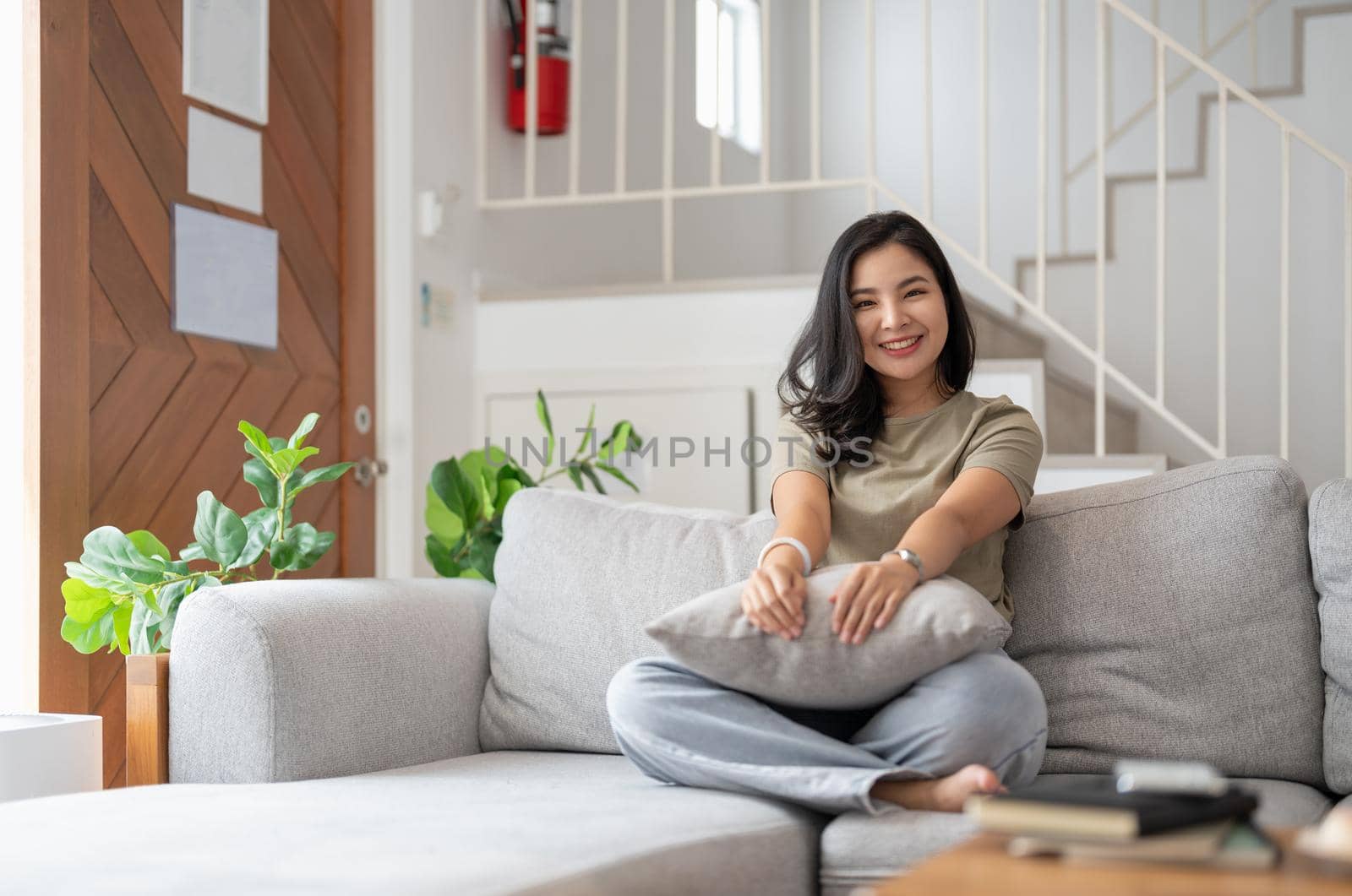 Portrait of smiling happy cheerful beautiful pretty asian woman relaxing on cozy sofa.