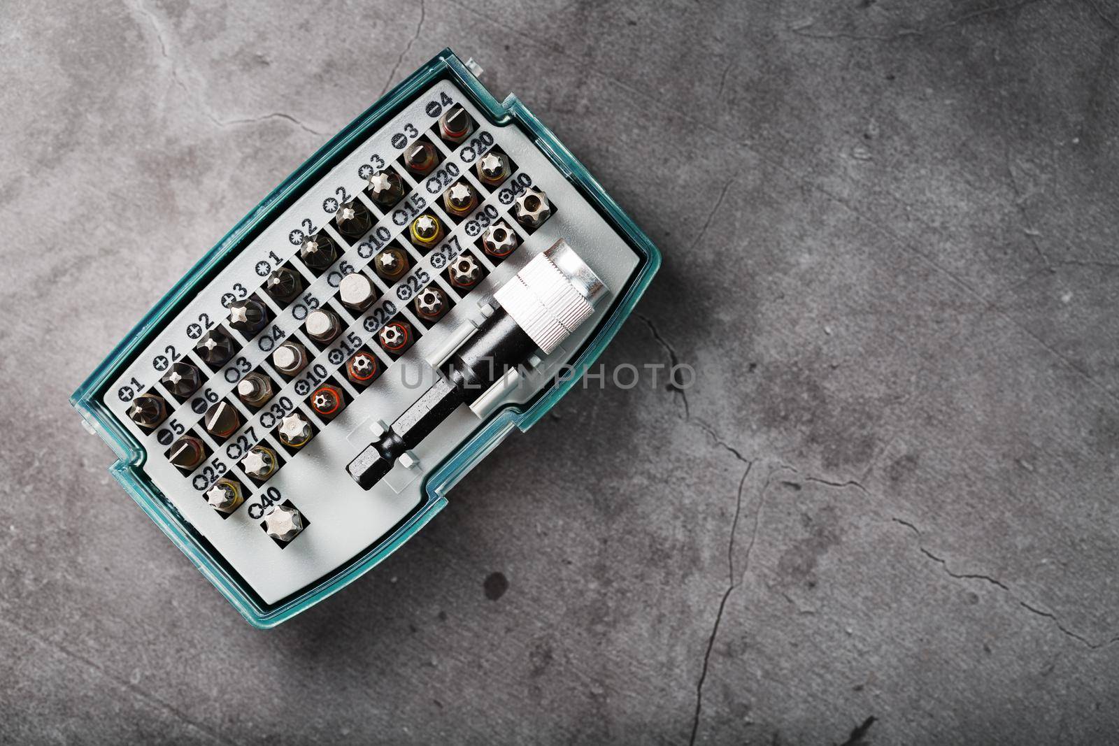 A set of different bits for screwdrivers and repairs in a box on a gray background by AlexGrec