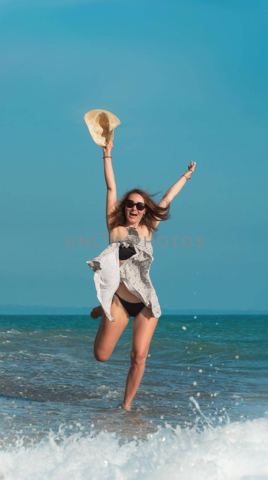 a beautiful girl in a swimsuit in summer on the seashore happily having fun on the water with emotions by Rotozey