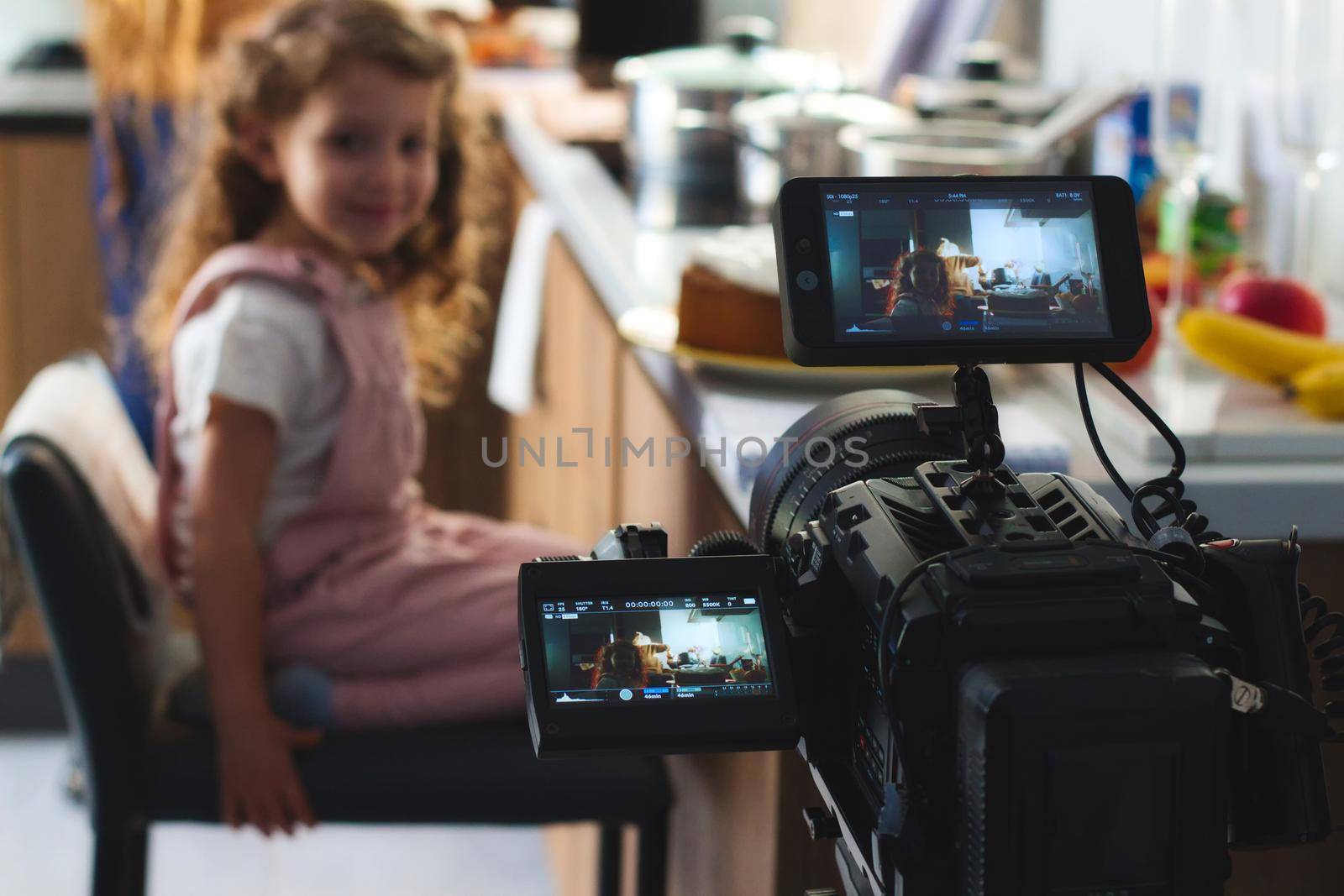 Video camera filming a movie scene with a young girl in the background by tennesseewitney