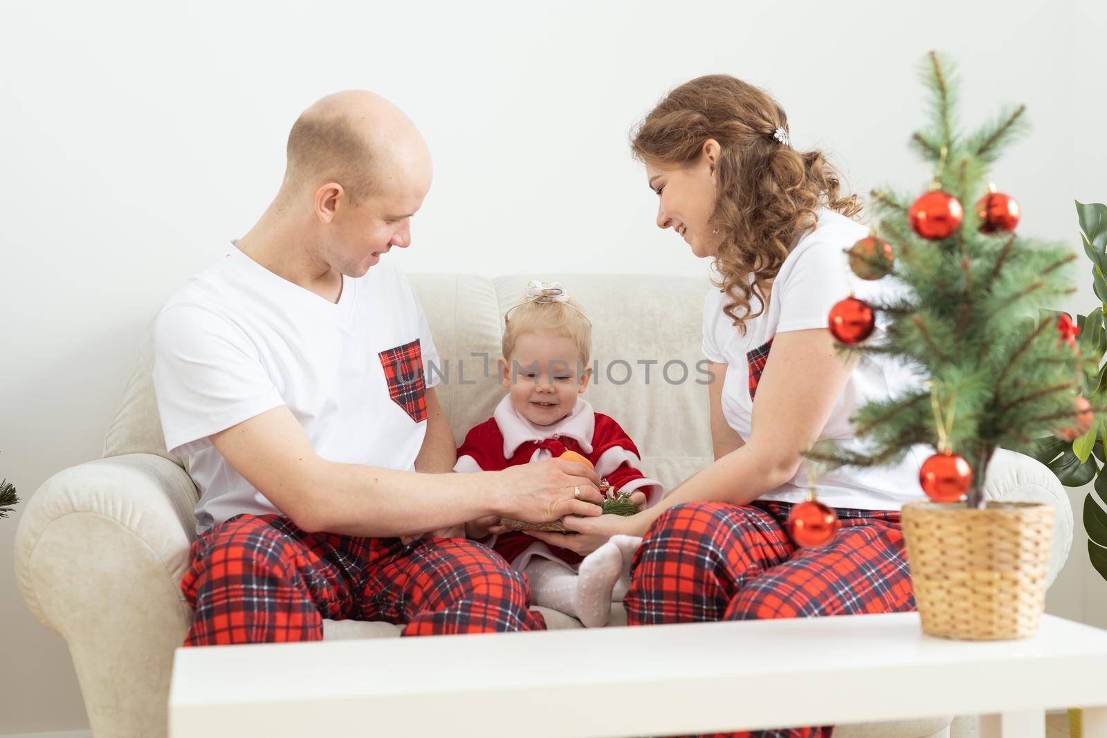 Baby child with hearing aid and cochlear implant having fun with parents in christmas room. Deaf , diversity and health concept by Satura86