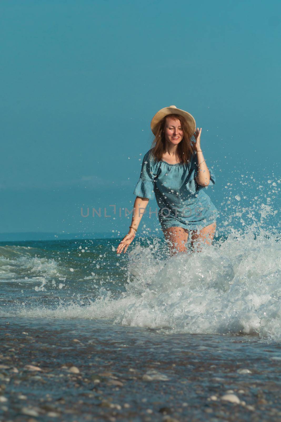 the beautiful girl in a swimsuit in summer on the seashore happily having fun on the water with emotions