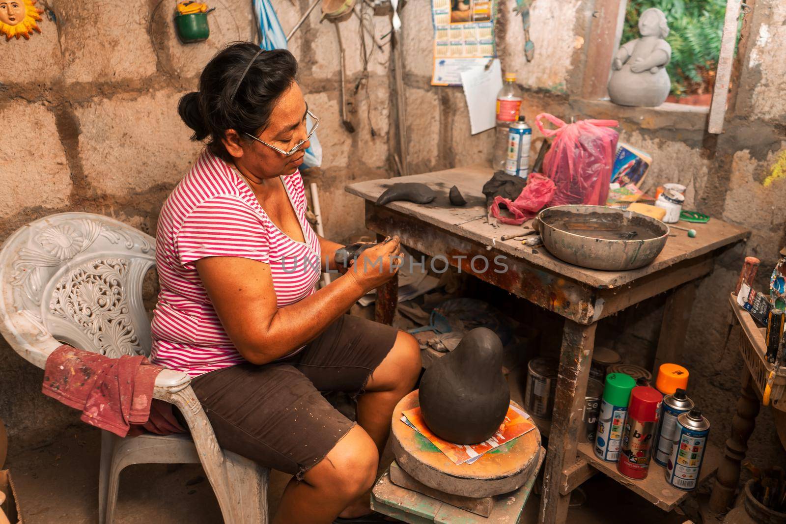 Craftswoman from Nicaragua molding clay pieces in her workshop by cfalvarez