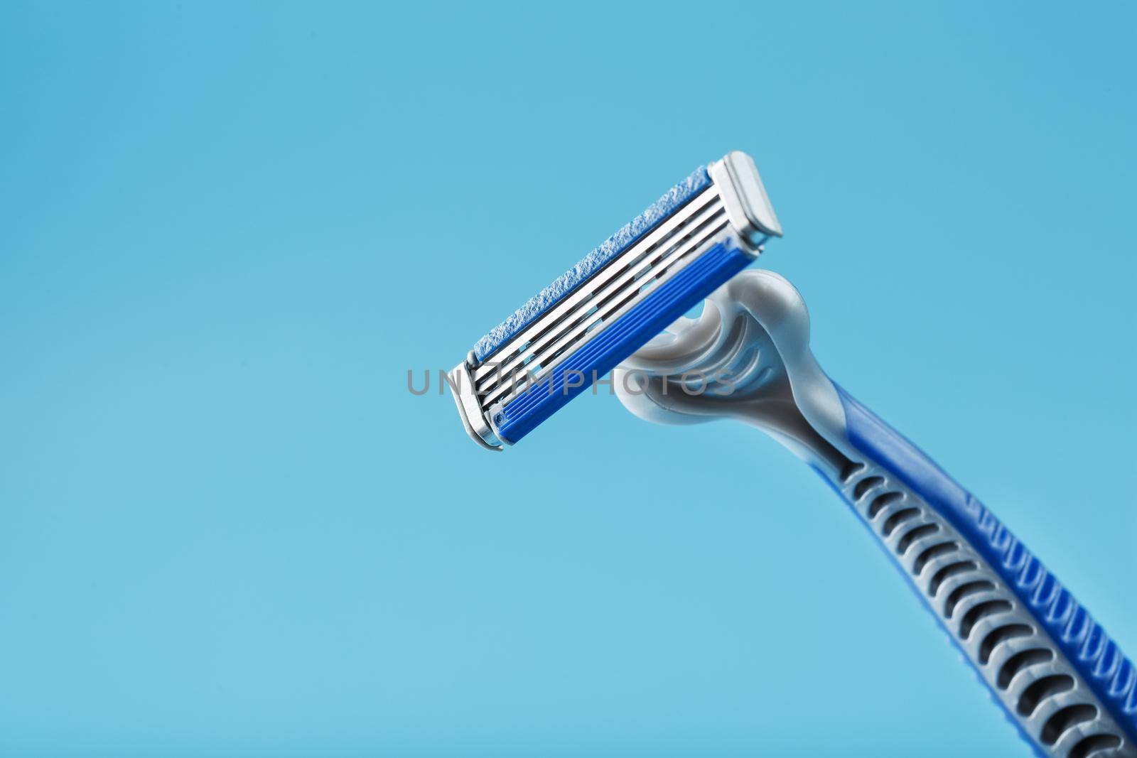 Shaving machine with three blades on a blue background close-up free space