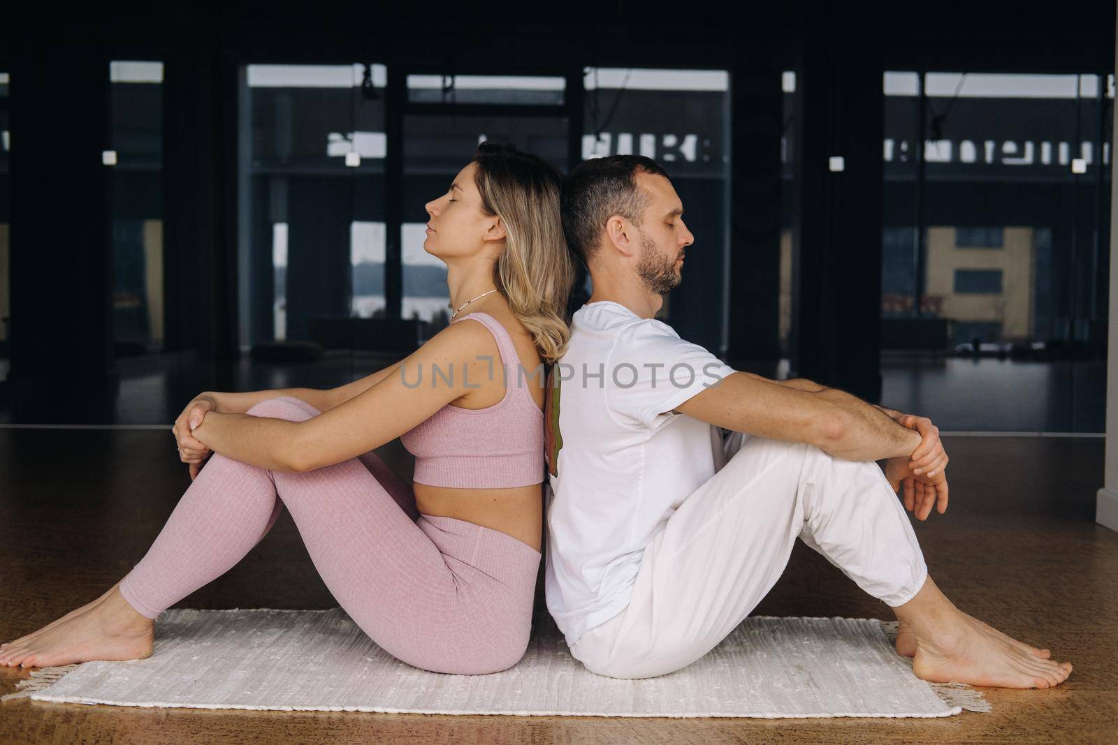 a woman and a man are engaged in pair gymnastics yoga in the gym by Lobachad