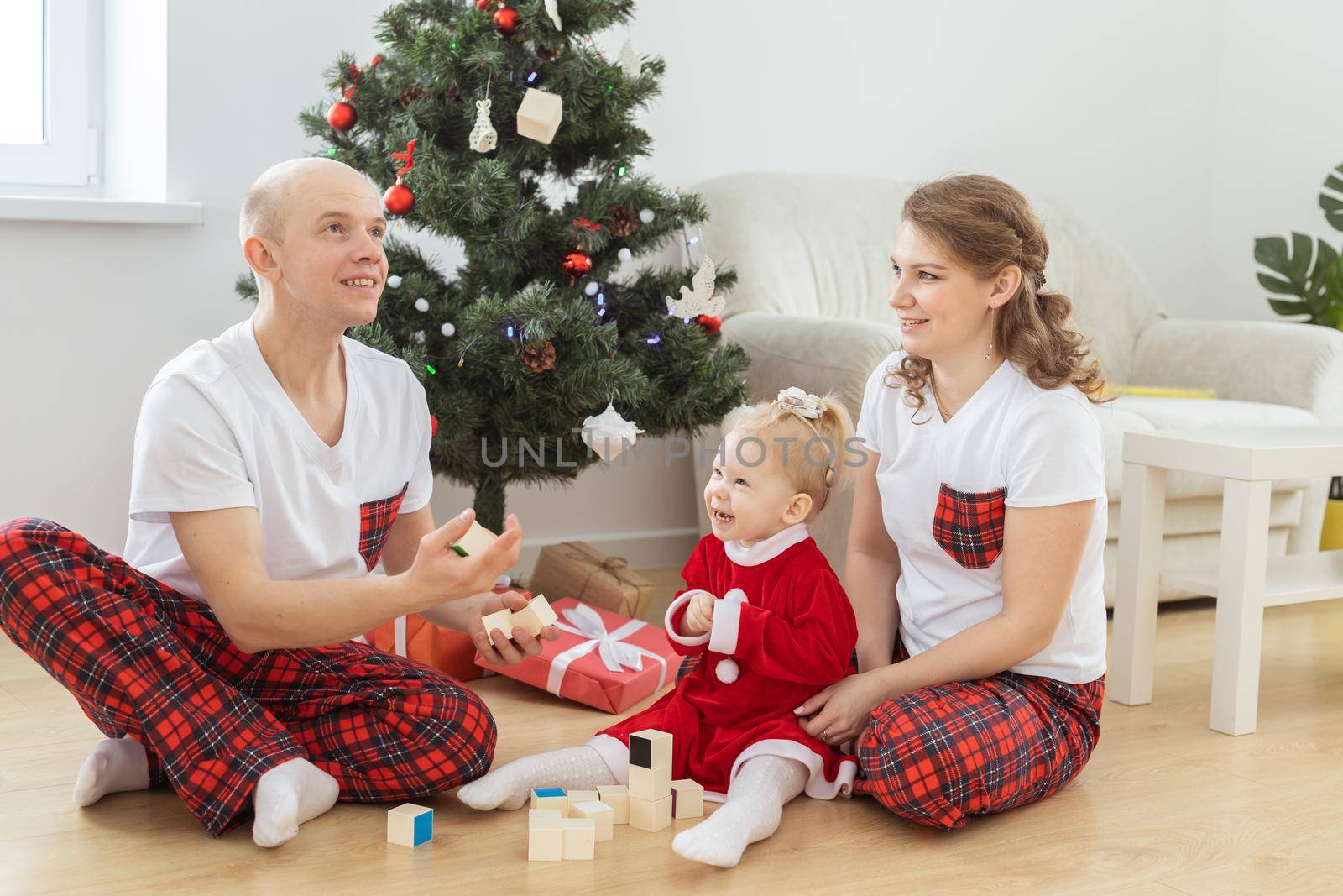 Baby child with hearing aid and cochlear implant having fun with parents in christmas room. Deaf and health