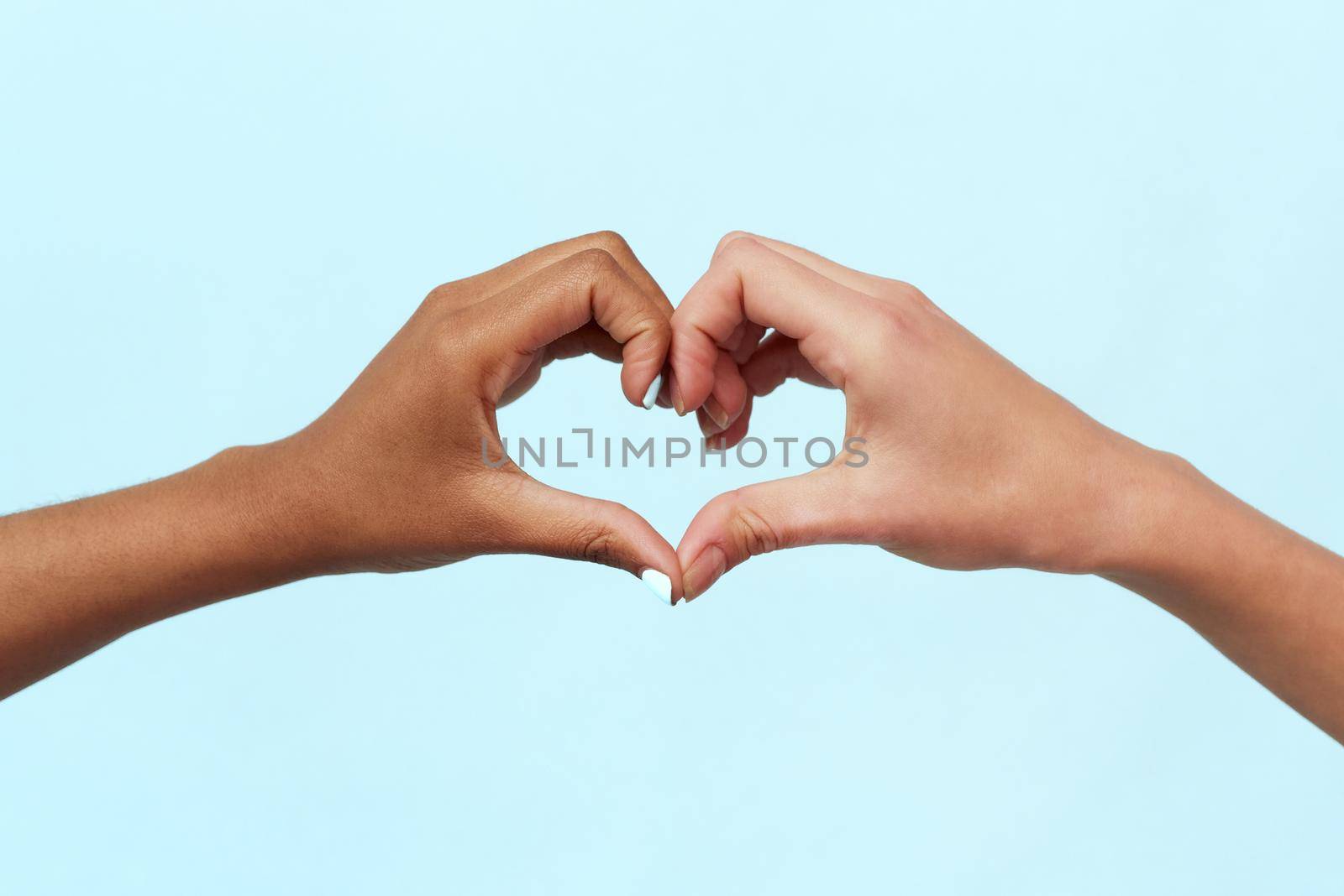 Caucasian and black african american woman showing heart gesture on blue background. Concept against racism, equality and unity, world peace