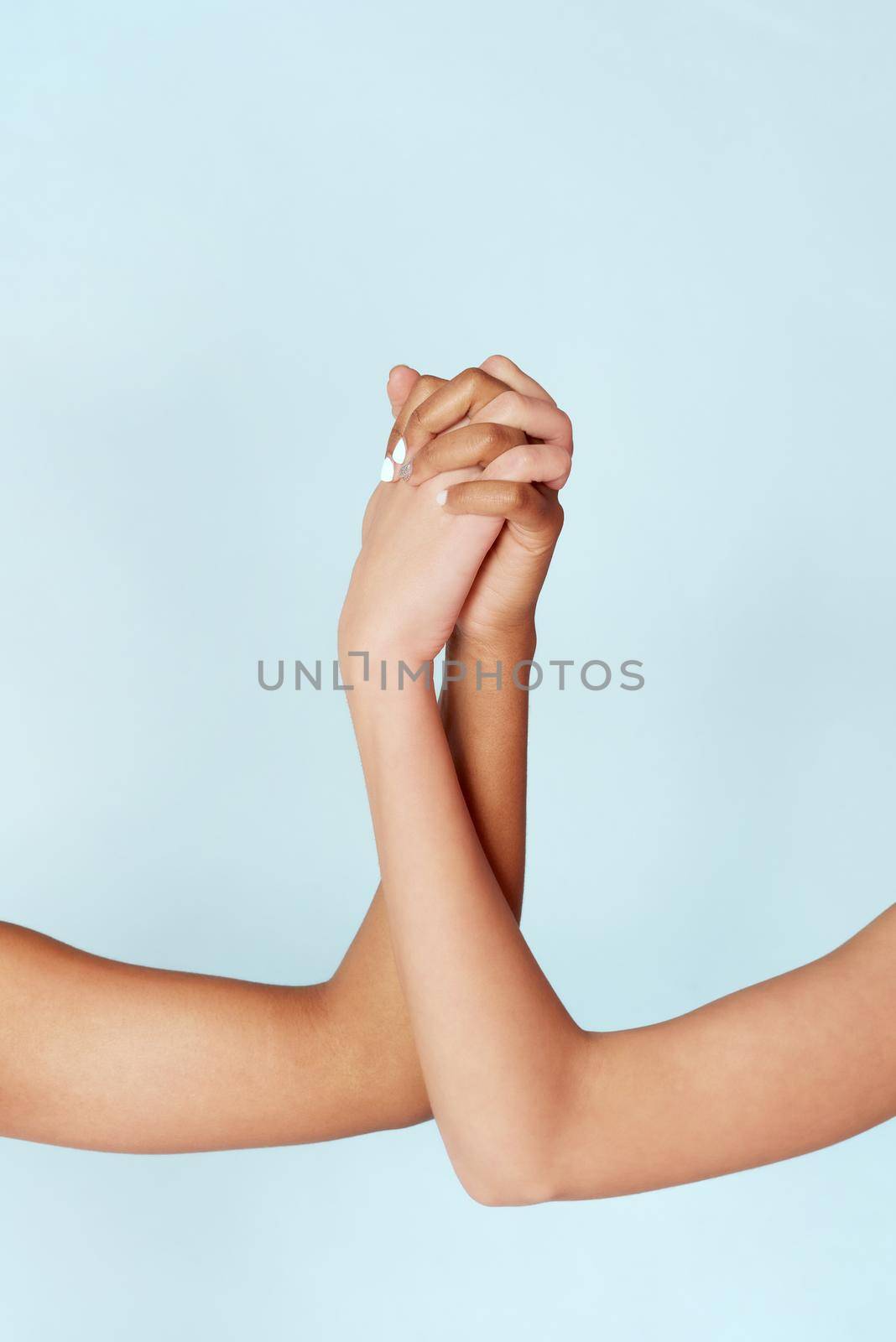 White and black women hold hands with clasped fingers. Diverse hands showing unity. Stop racism. Everyone's lives matter.