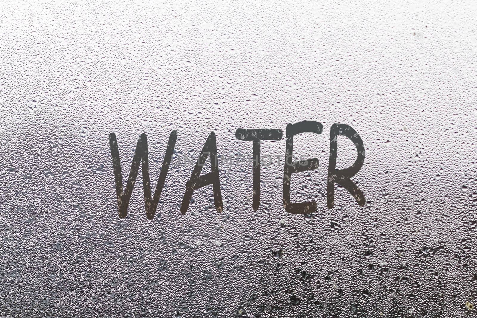 Word water written on foggy window, closeup view.