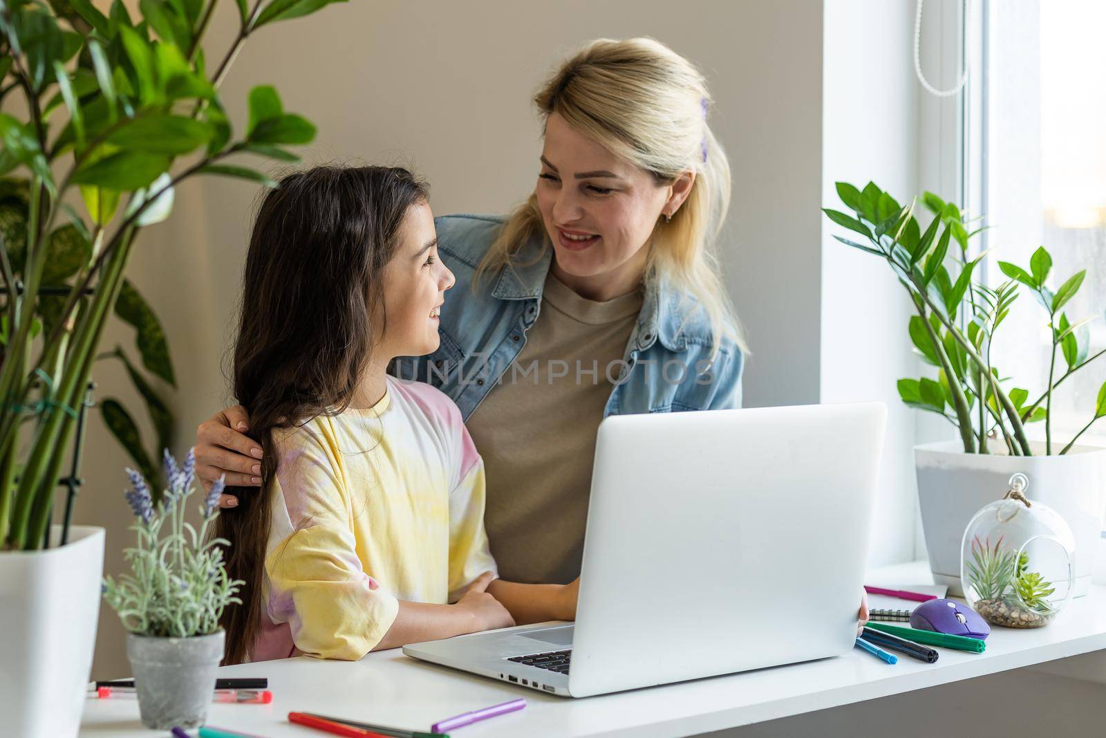 Happy mother with little kid daughter having fun online with application, watching video cartoons or playing game on laptop together, young babysitter or nanny teaching child girl to use computer by Andelov13