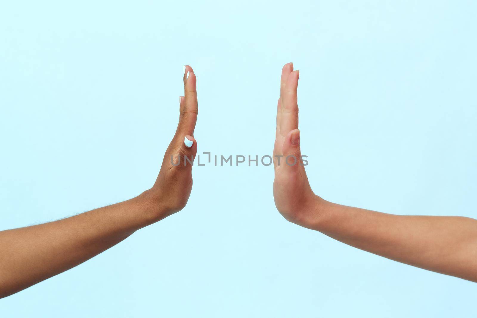 White Caucasian female hands and black African American hands show a stop sign. The problem of racism.