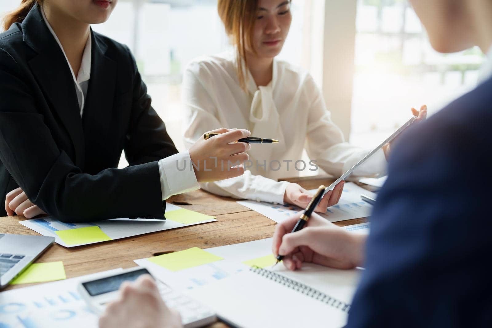 Businesswoman holding pen pointing at tablet to discuss marketing strategy summaries with colleagues in meetings, teamwork, investment planning.