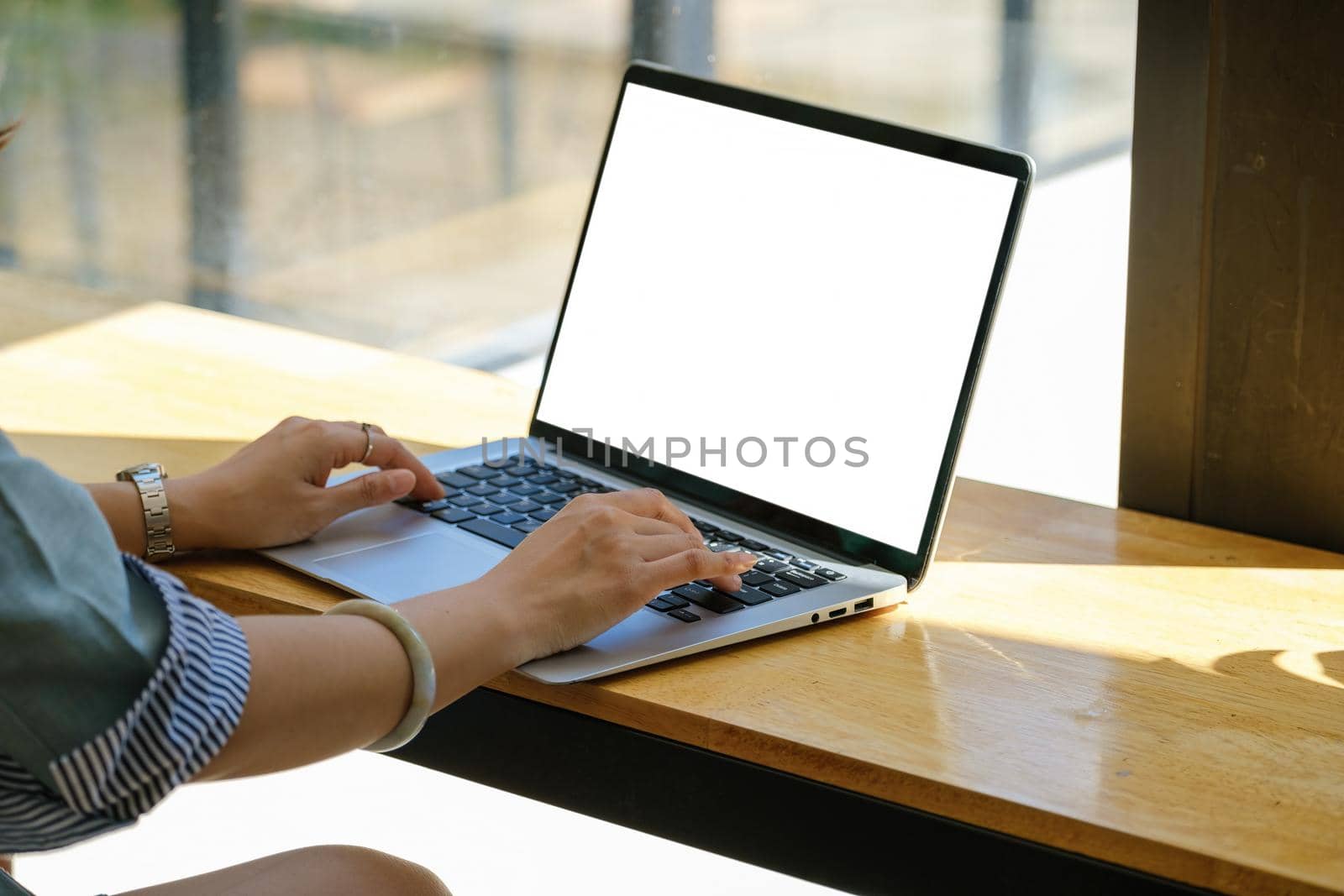 A woman using a computer laptop with a blank white screen. The blank space on the white screen can be used to write a message or place an image.