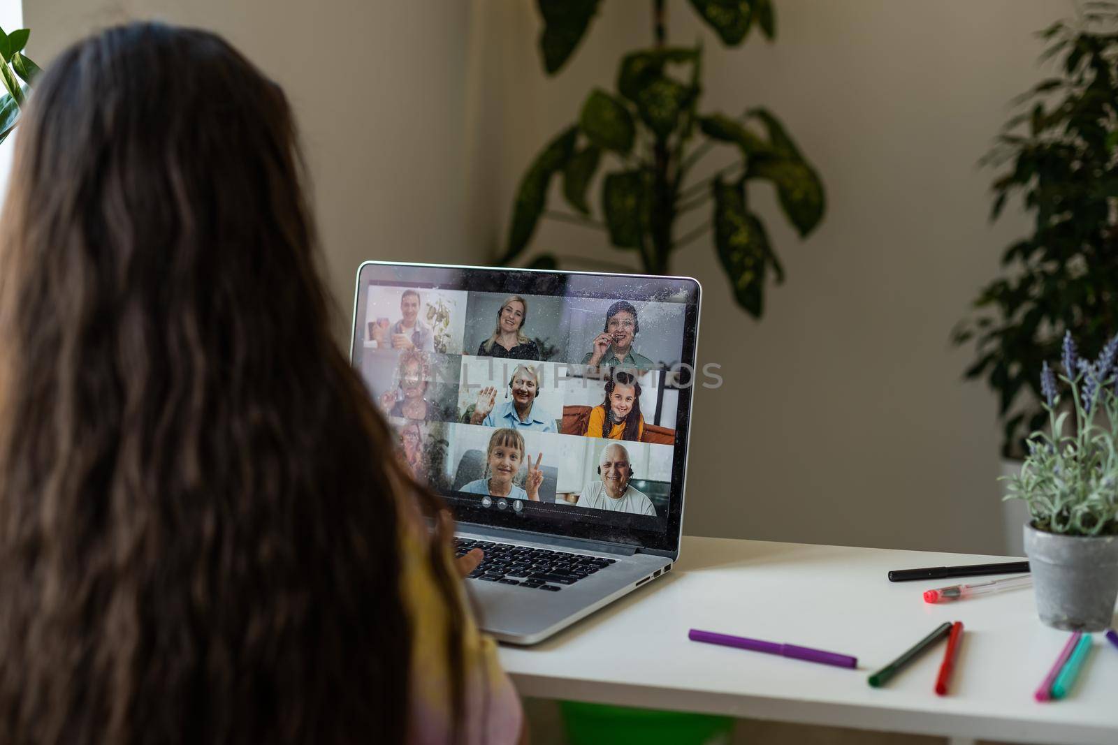 Home schooling. A girl is sitting at a table with a laptop during an online video chat of a school lesson with a teacher and class. Concept of distance education. Self-isolation in quarantine