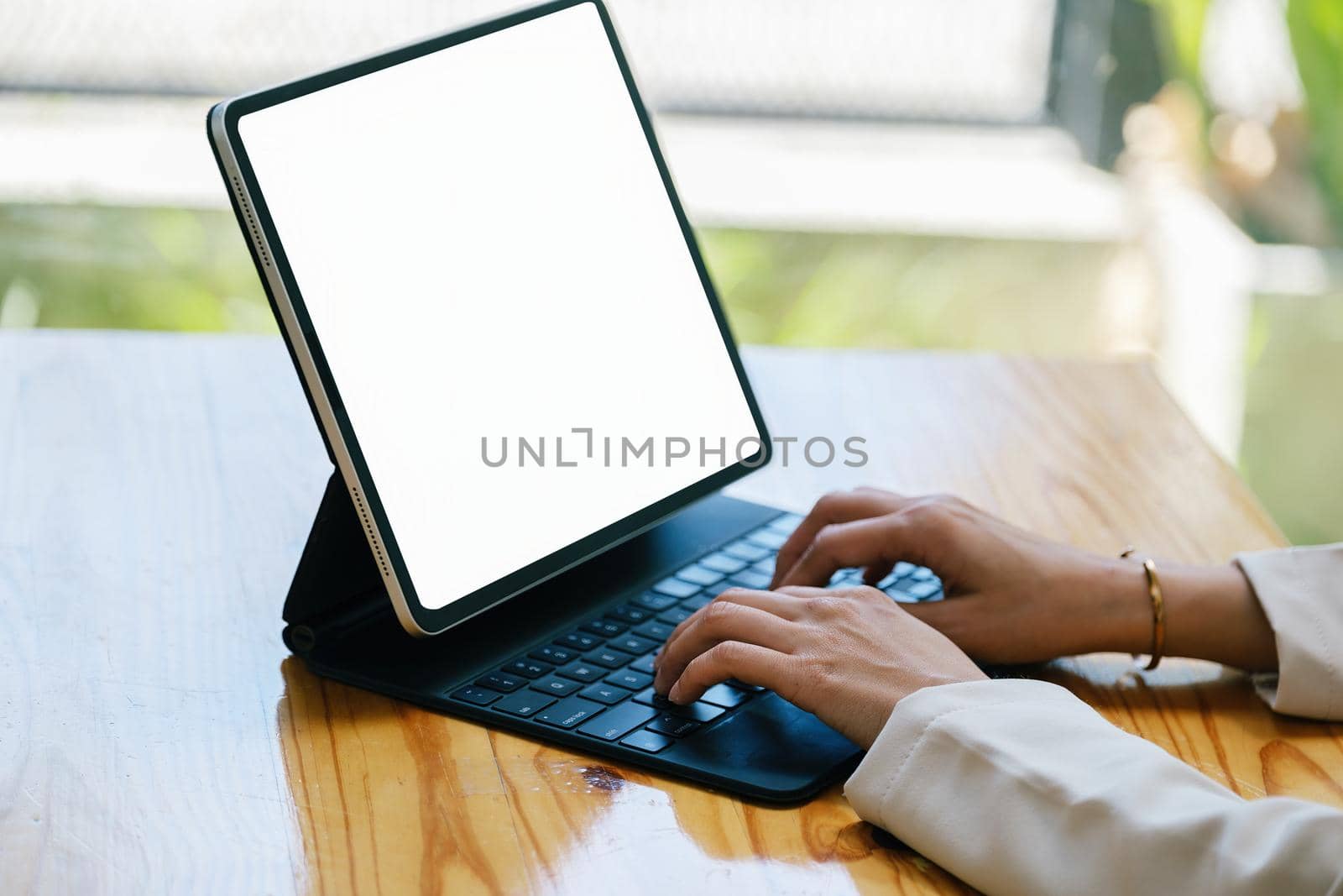 A woman using a tablet with a blank white screen. The blank space on the white screen can be used to write a message or place an image.