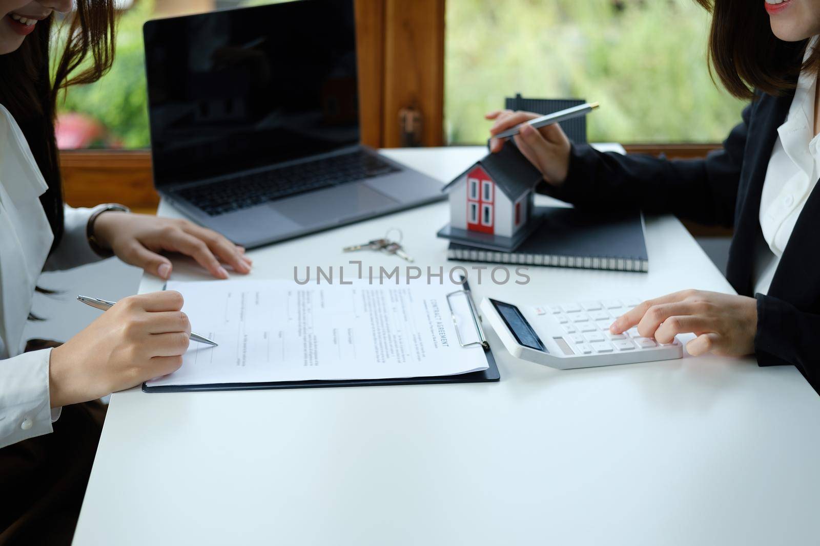 Guarantee, mortgage, contract, contract, signed, real estate agent or bank officer pointing a calculator, submits a bid with a customer to buy a home before signing to make a deal.