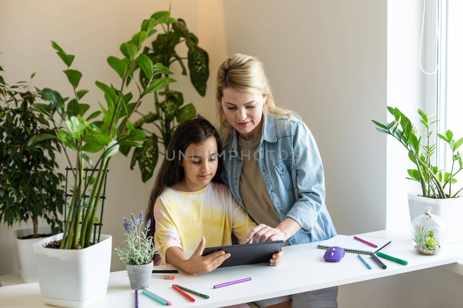 Back to school. Happy child and adult are sitting at desk. Girl doing homework or online education.