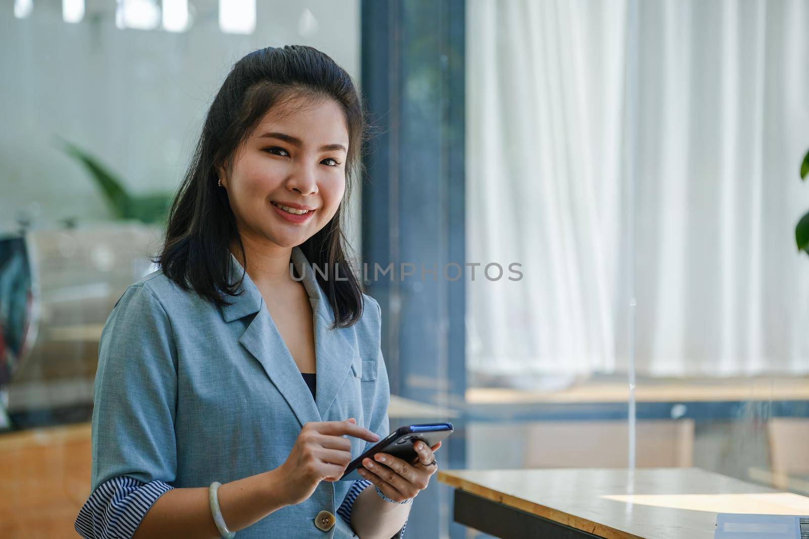 portrait of Asian women using smartphone mobile in capital planning to increase company profits.