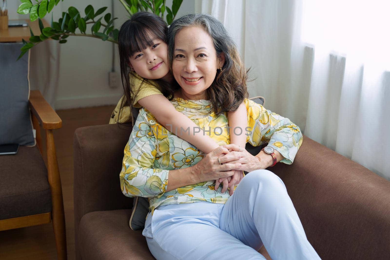 Asian portrait, grandma and granddaughter doing leisure activities and hugging to show their love and care for each other by Manastrong