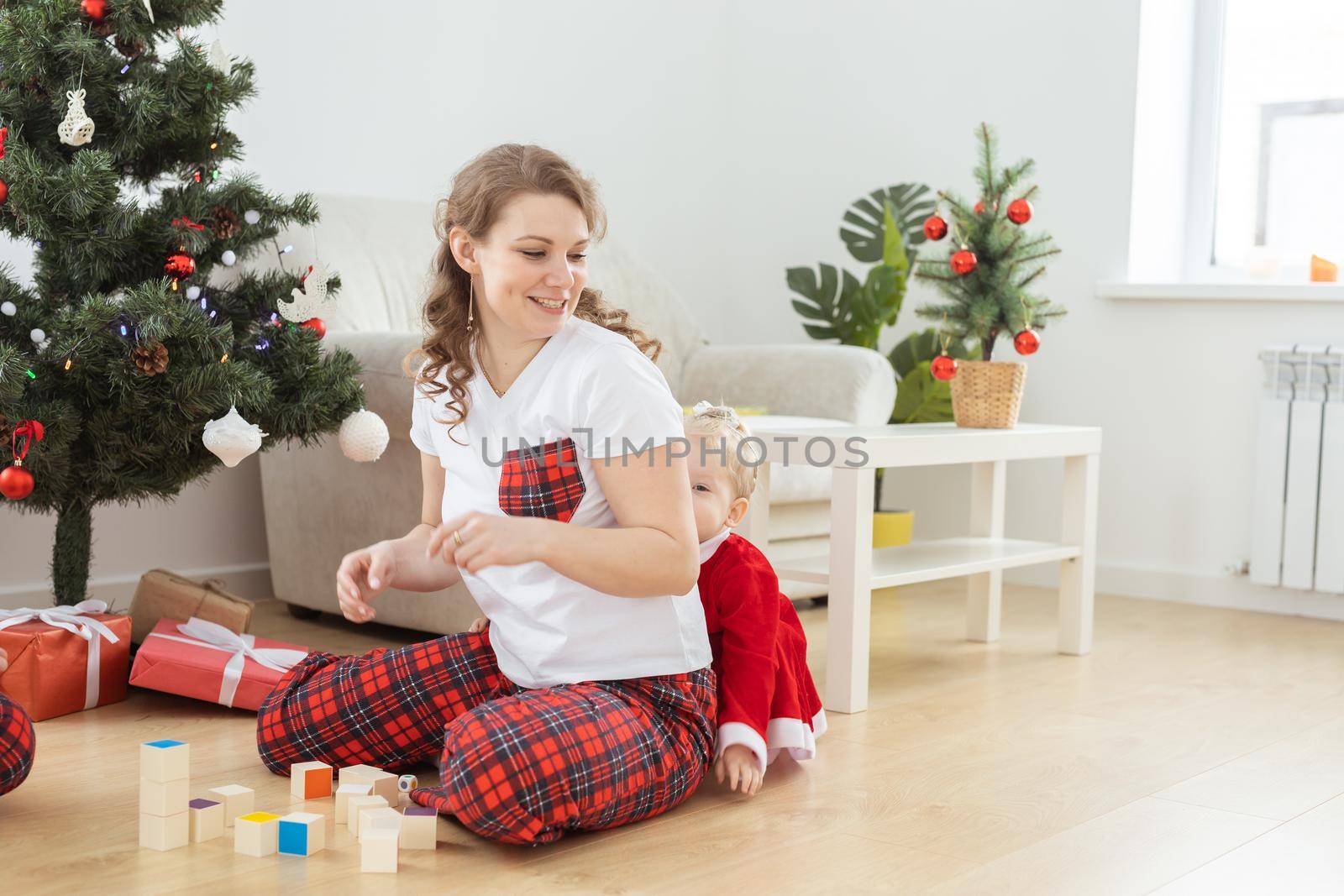 Toddler child with cochlear implant plays with mother near christmas tree copy space and place for advertising - deafness and innovating medical technologies for hearing aid by Satura86