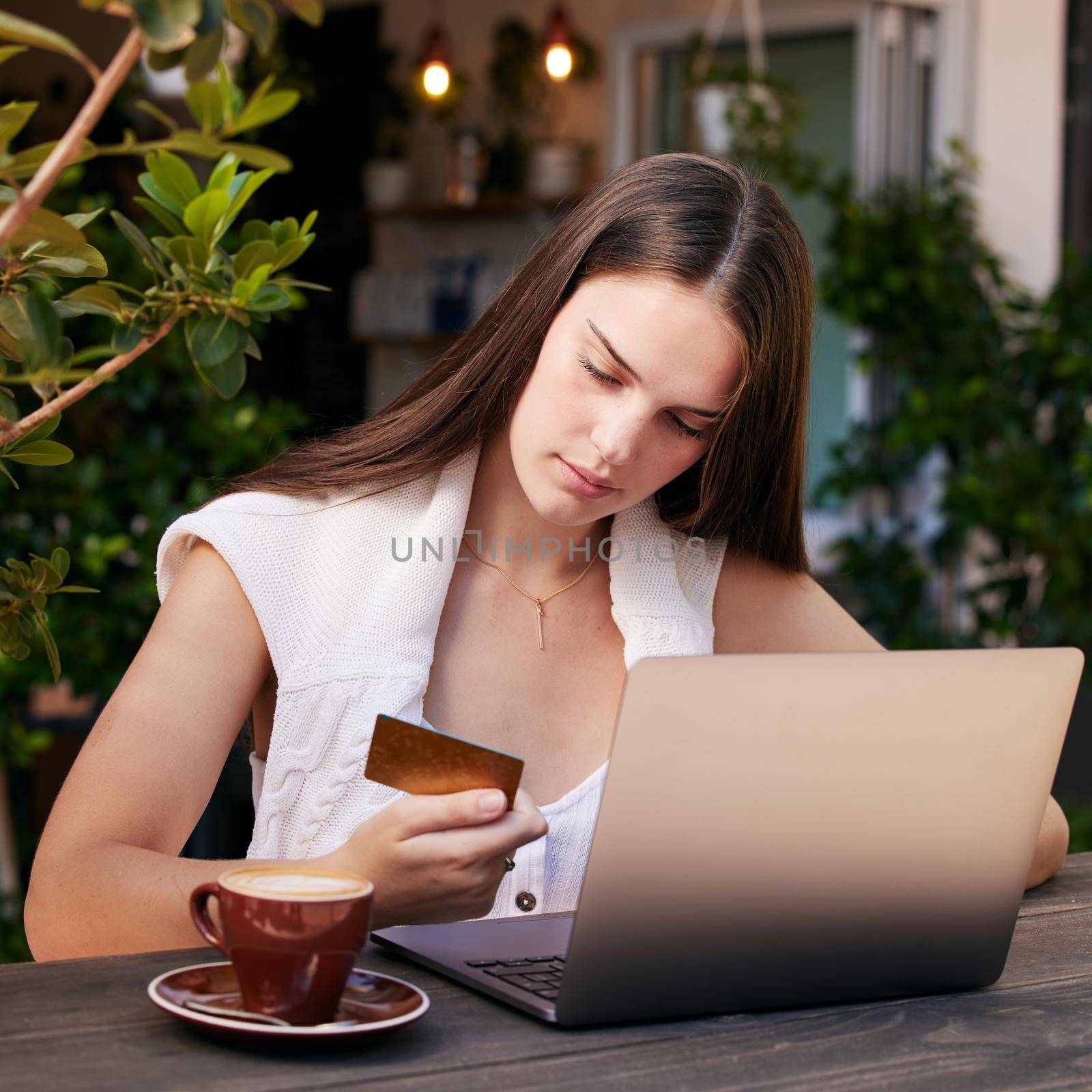 Shot of a young woman using her debit card to shop on her laptop.