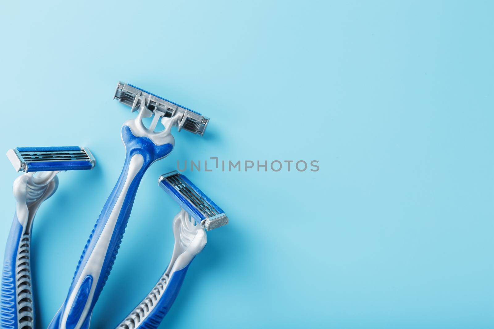 Three shaving machines on a blue background with free space, top view