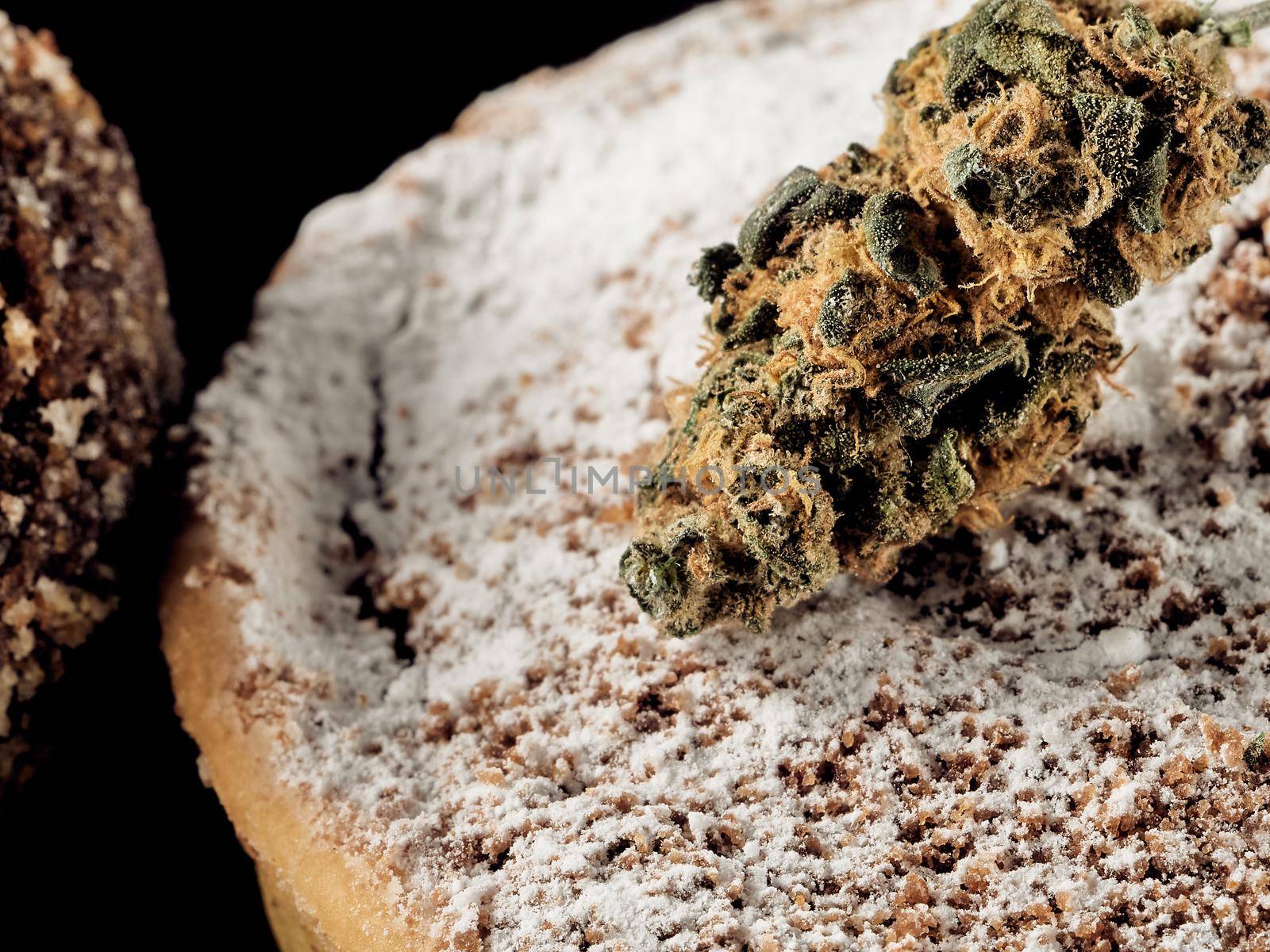 Vegan sugar-free cocoa truffles and medical cannabis bud on a slate plate. dark background. close-up. Horizontal orientation.