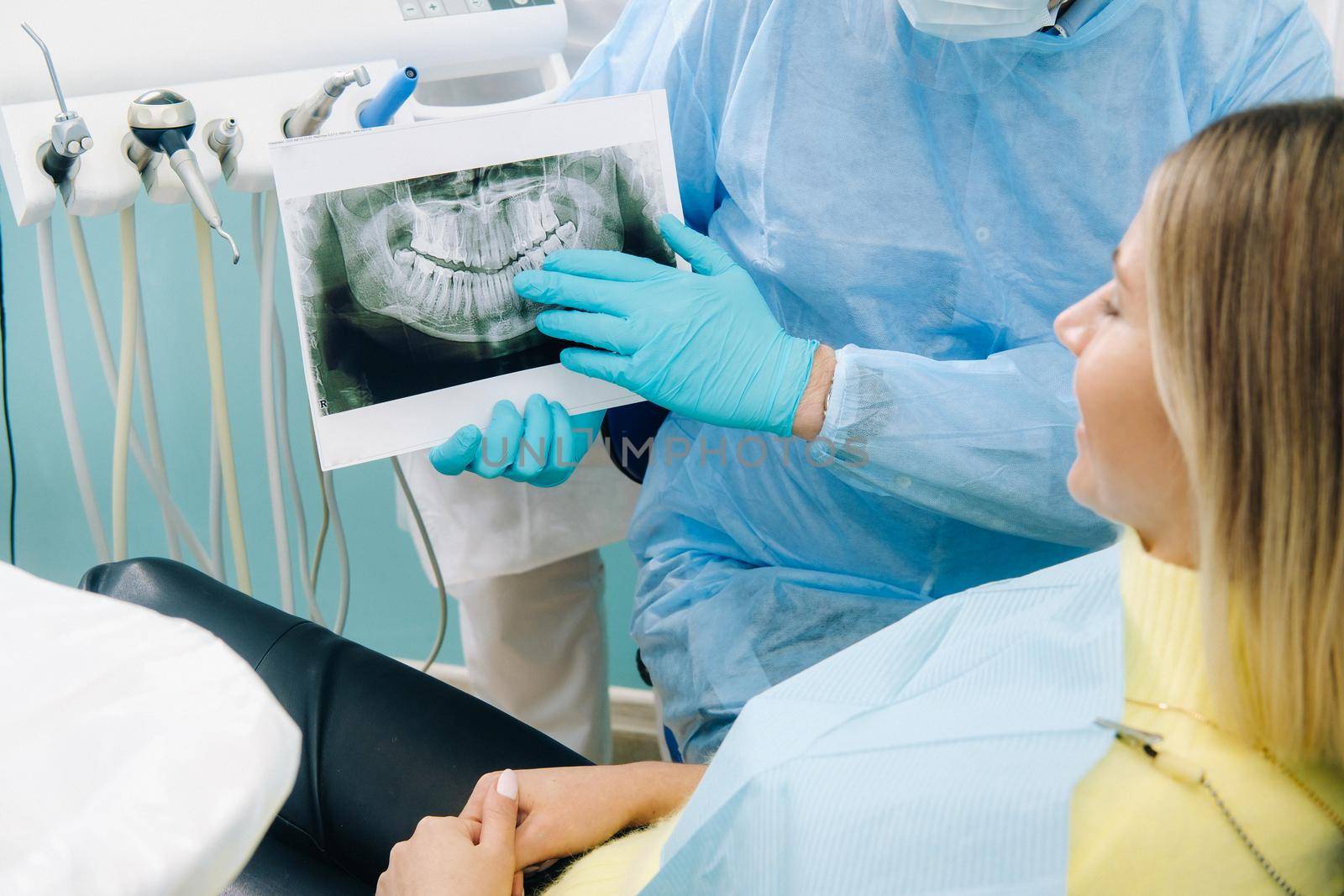 Dentist explaining the details of the X-ray to his patient in the office by Lobachad