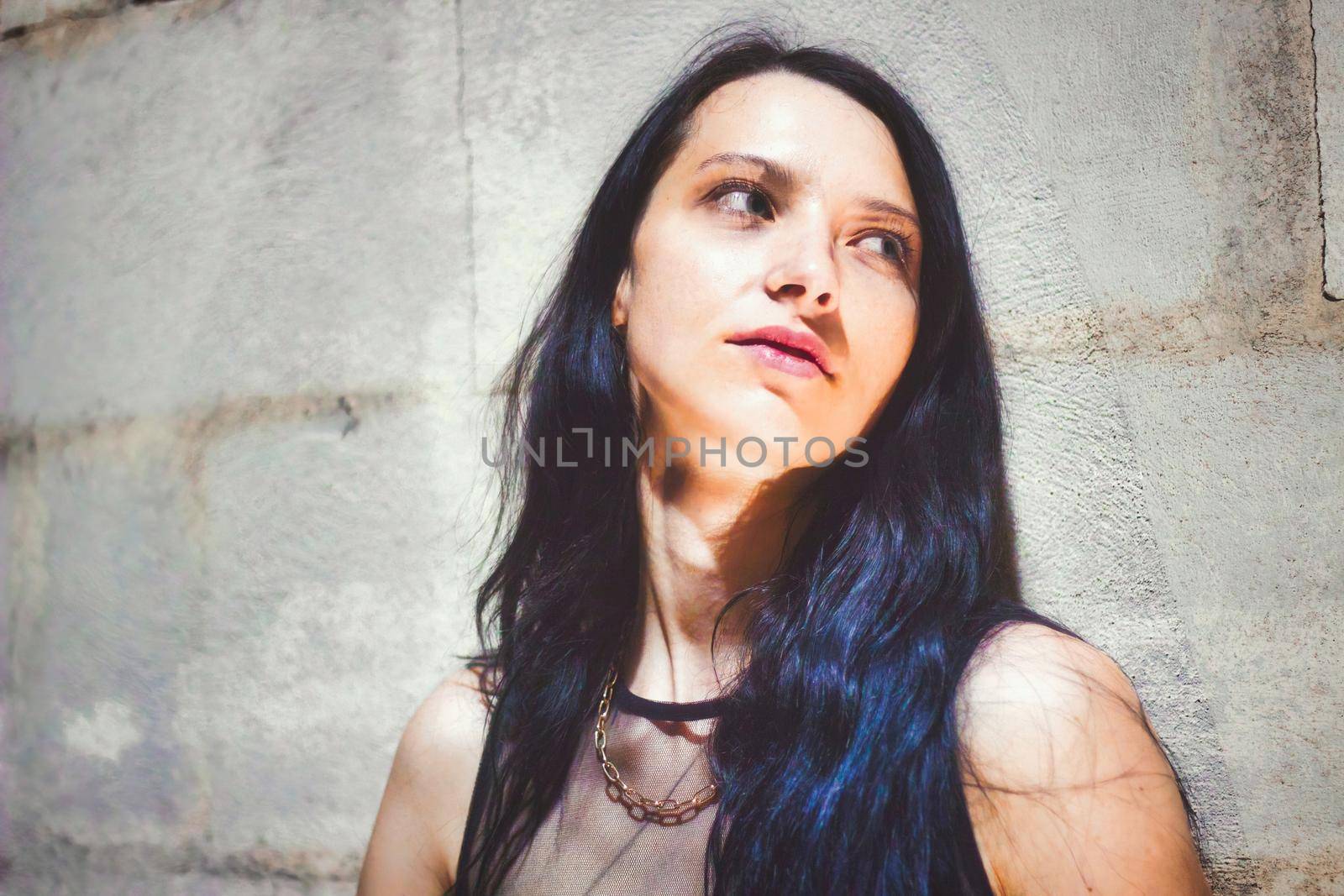 A goth girl leaning against a wall looking away from the camera