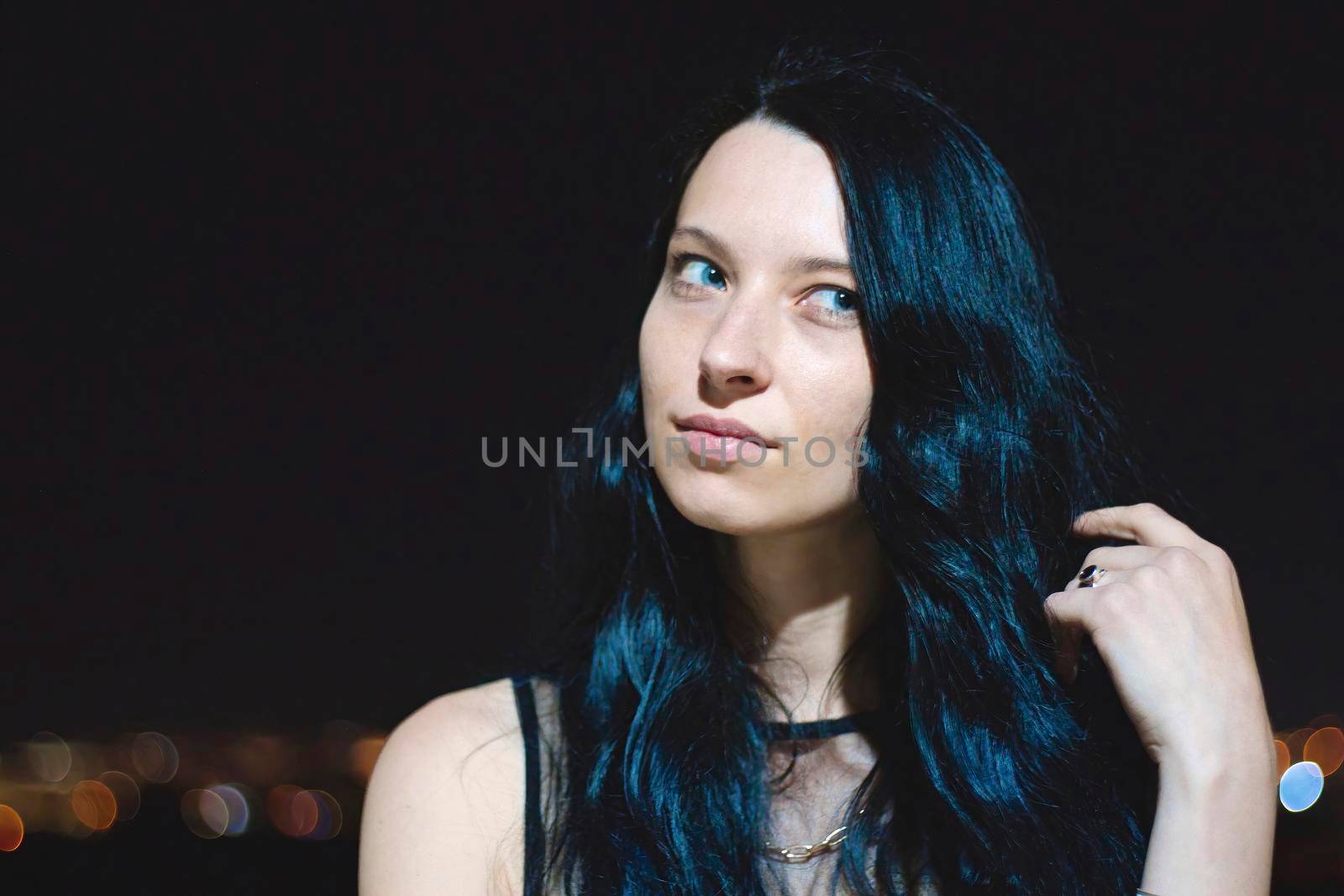 Portrait headshot of an attractive white Caucasian young woman with striking features against a night time dark background