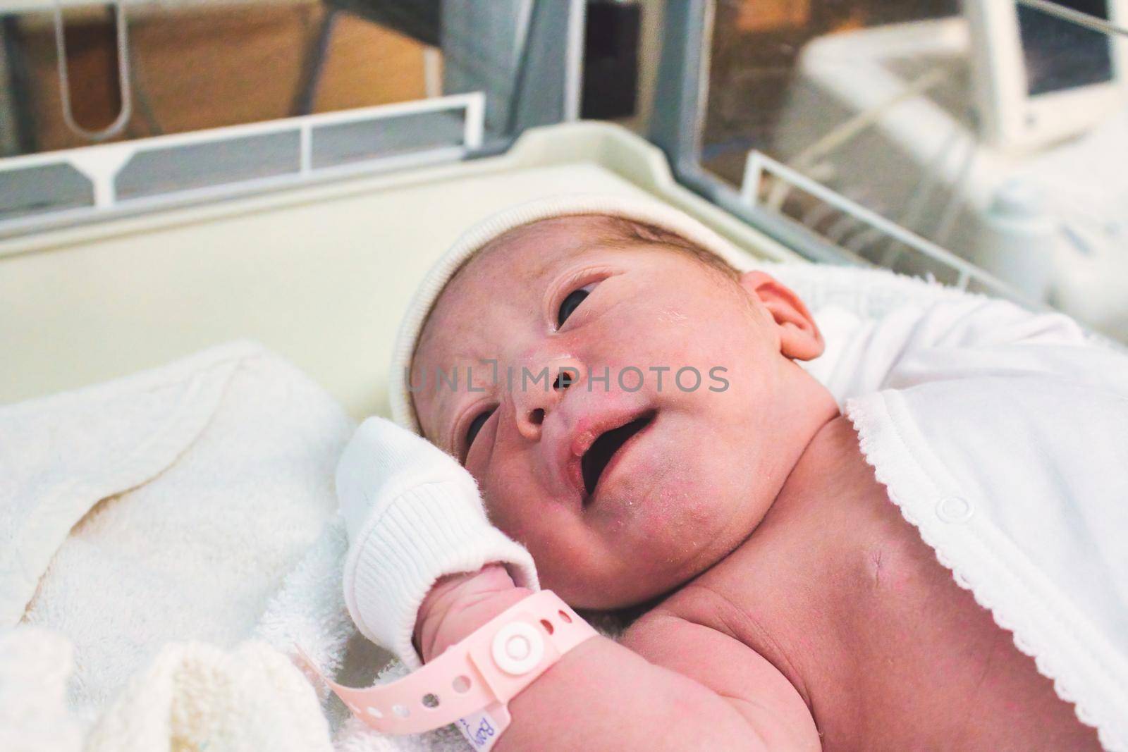 Newborn baby girl just born in hospital in the maternity ward with a plastic tag on her wrist by tennesseewitney
