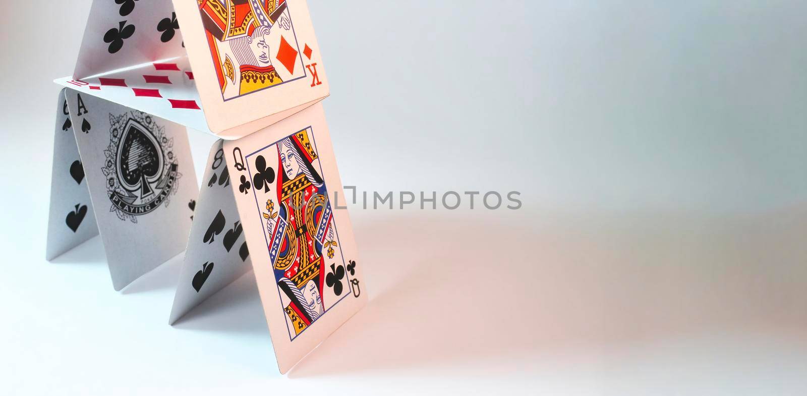 House of stacked playing cards against a white background with room for text placement by tennesseewitney